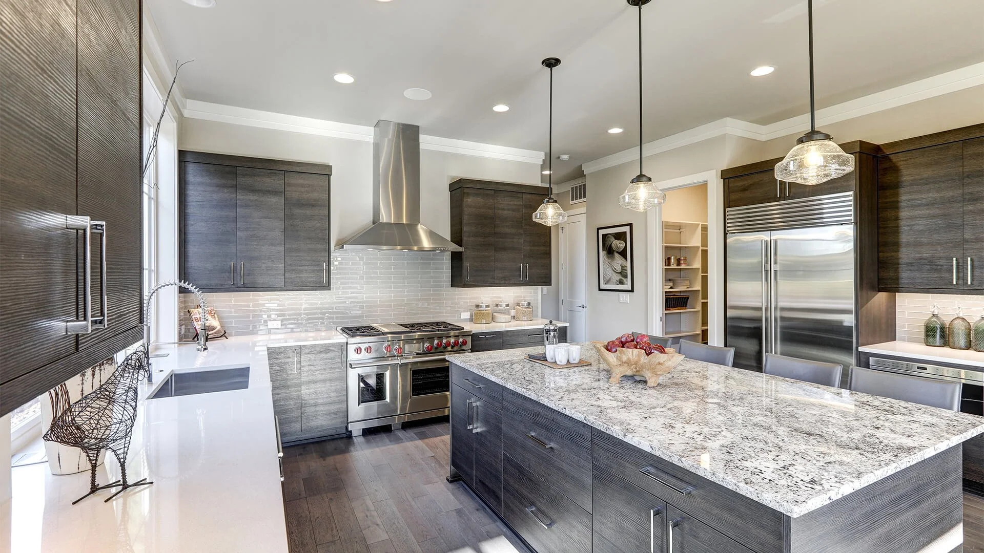 Custom kitchen remodel by HM Remodeling in South Bend Indiana featuring dark cabinetry, granite island countertop, stainless steel appliances, and tile backsplash