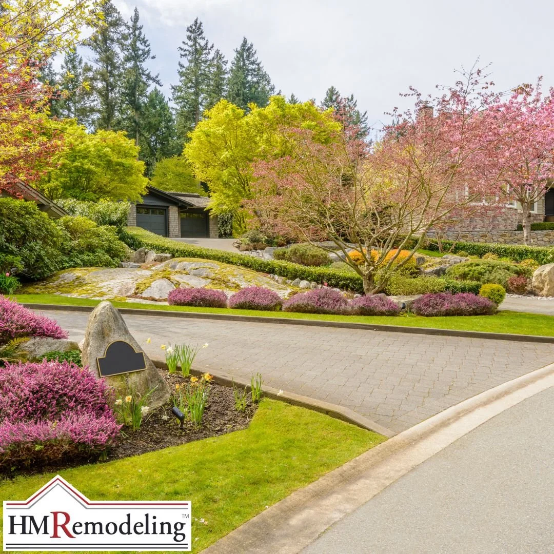 Spring residential curb appeal featuring flowering cherry and ornamental trees, layered landscape beds with heather and ornamental grasses, and a paver driveway in South Bend, Indiana