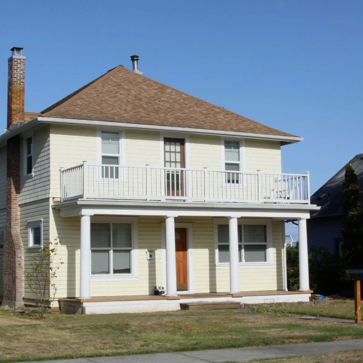 Updated single-story home exterior with natural stone gable accent, tan vinyl siding, dimensional shingle roof, and manicured lawn in South Bend and Michiana