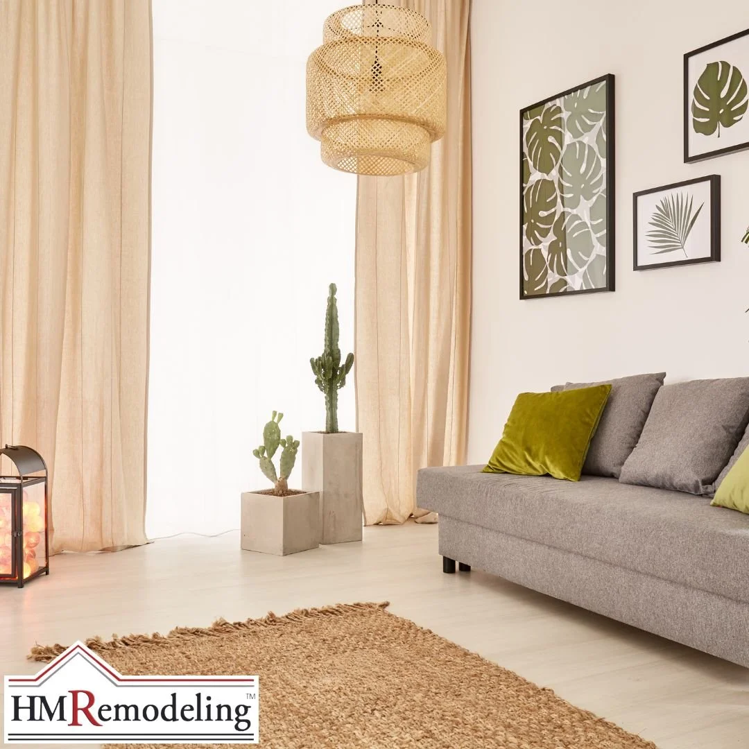 Bright living room with woven rattan pendant light, floor-to-ceiling linen curtains, concrete planter with cactus, botanical framed wall art, and gray sofa in a refreshed South Bend, Indiana interior