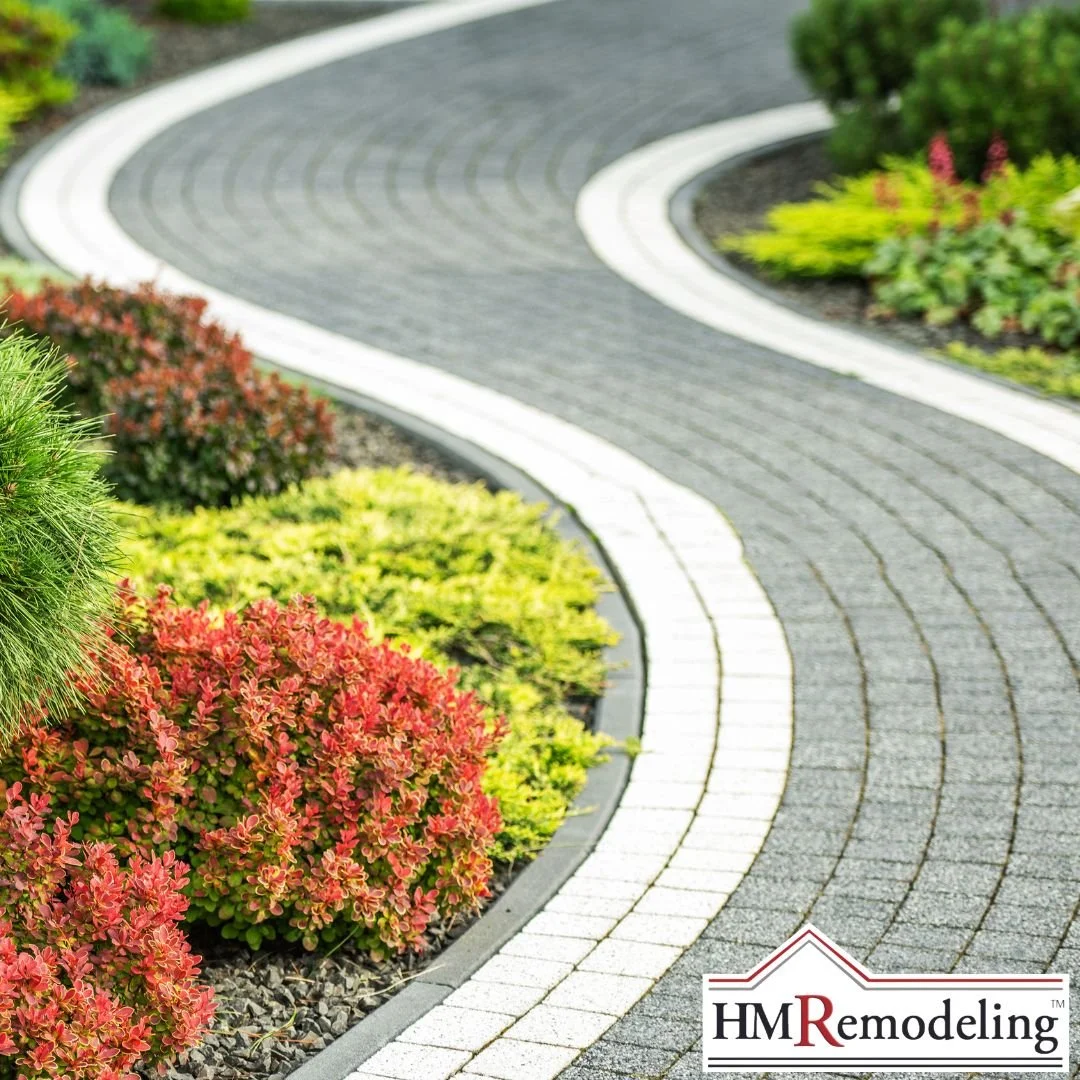 Curved gray paver walkway with white border accent edging flanked by manicured red and yellow-green shrubs in mulched landscape beds, exterior upgrade in South Bend, Indiana