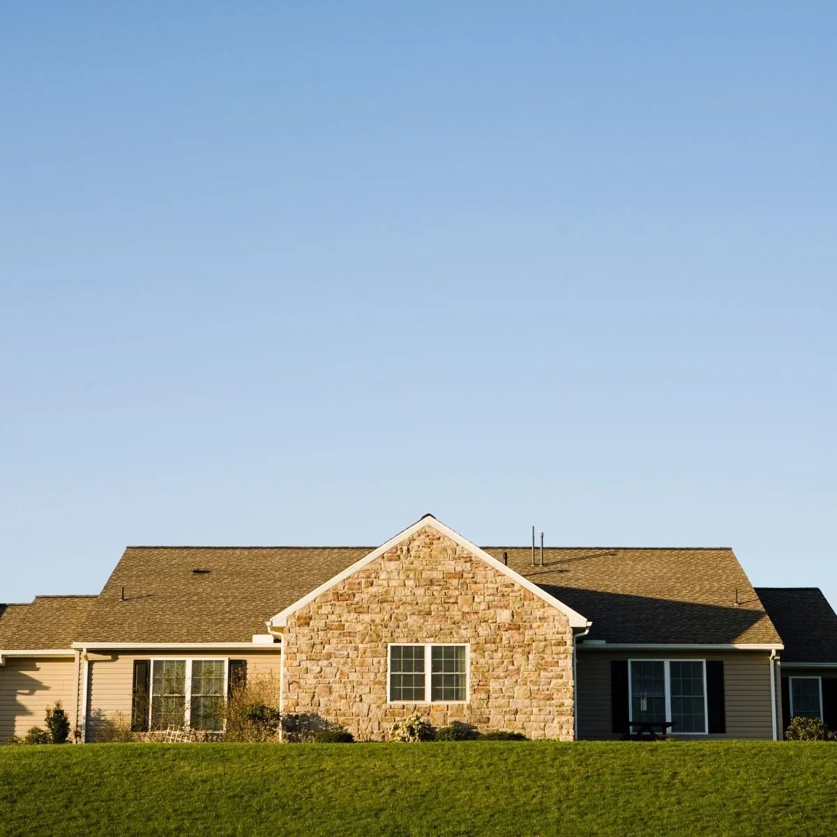 Historic multi-story brick building exterior with arched windows, decorative brick detailing, clay tile roof, dormers, and climbing ivy representing older home restoration in South Bend and Michiana