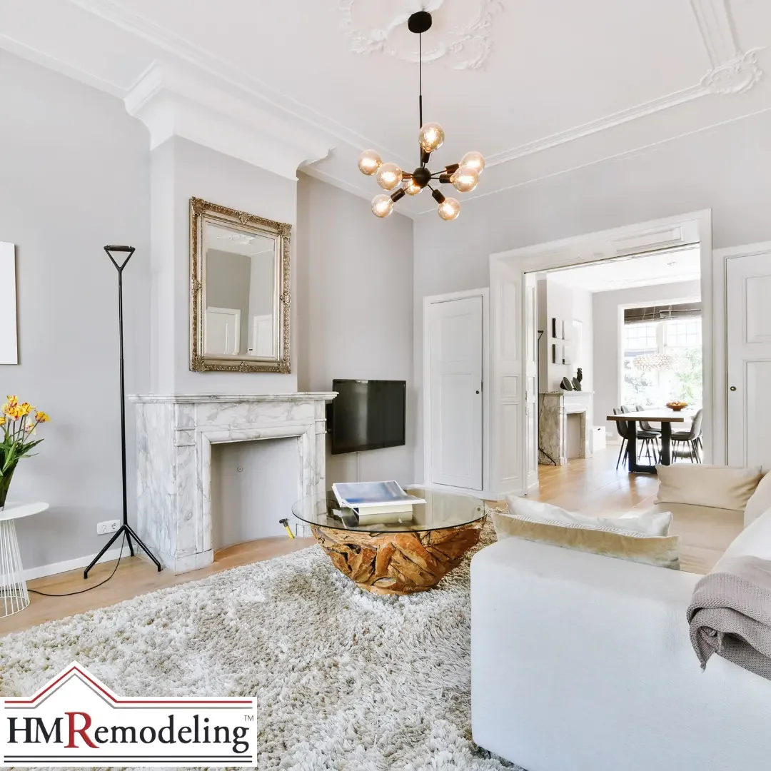 A refined South Bend, Indiana living room featuring detailed white crown molding, a marble fireplace surround, light gray walls, a modern sputnik chandelier, and an open view into a dining area with natural light
