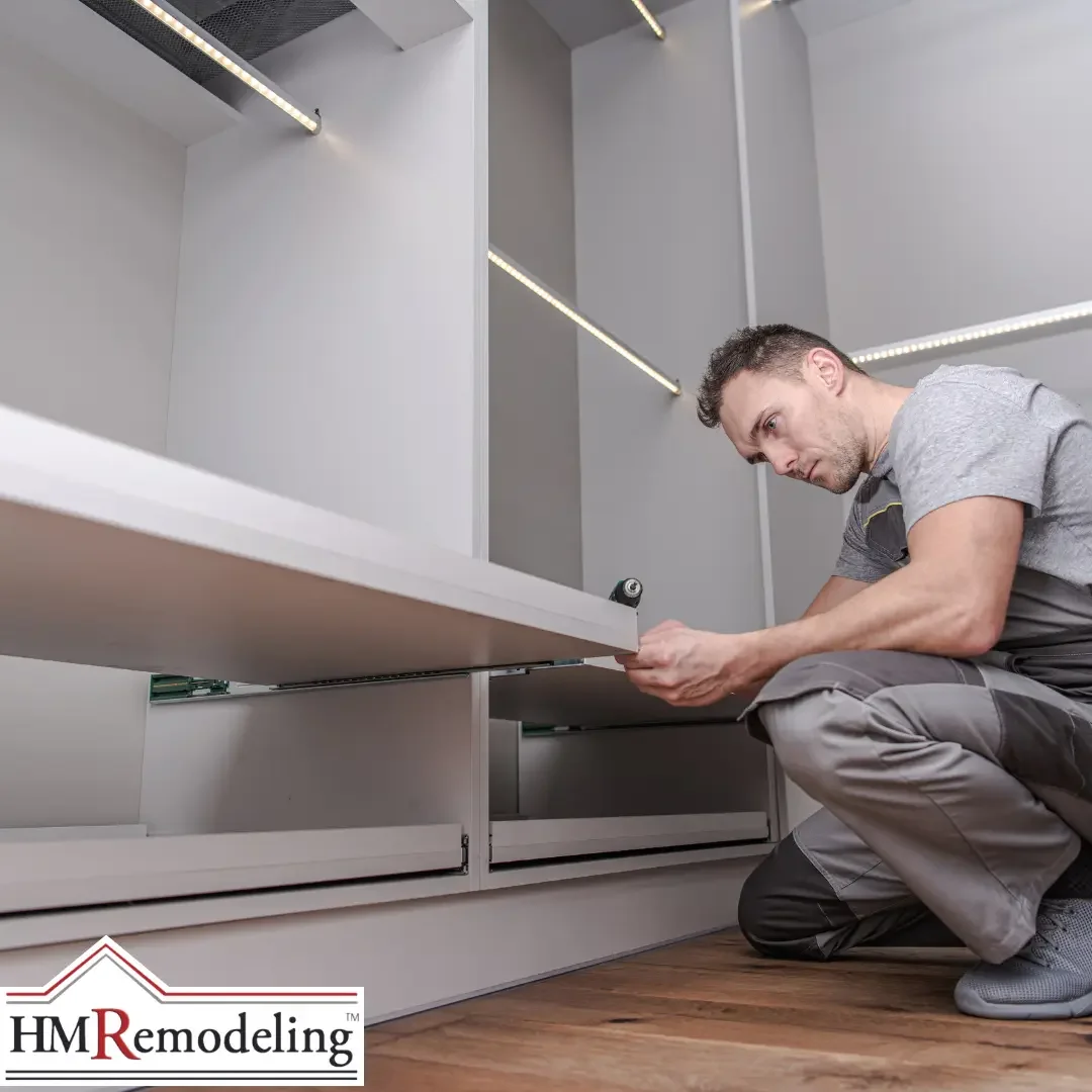 A contractor installing a drawer into a white built-in mudroom cabinet system with LED strip lighting on multiple shelves and hardwood flooring in a South Bend, Indiana home remodel