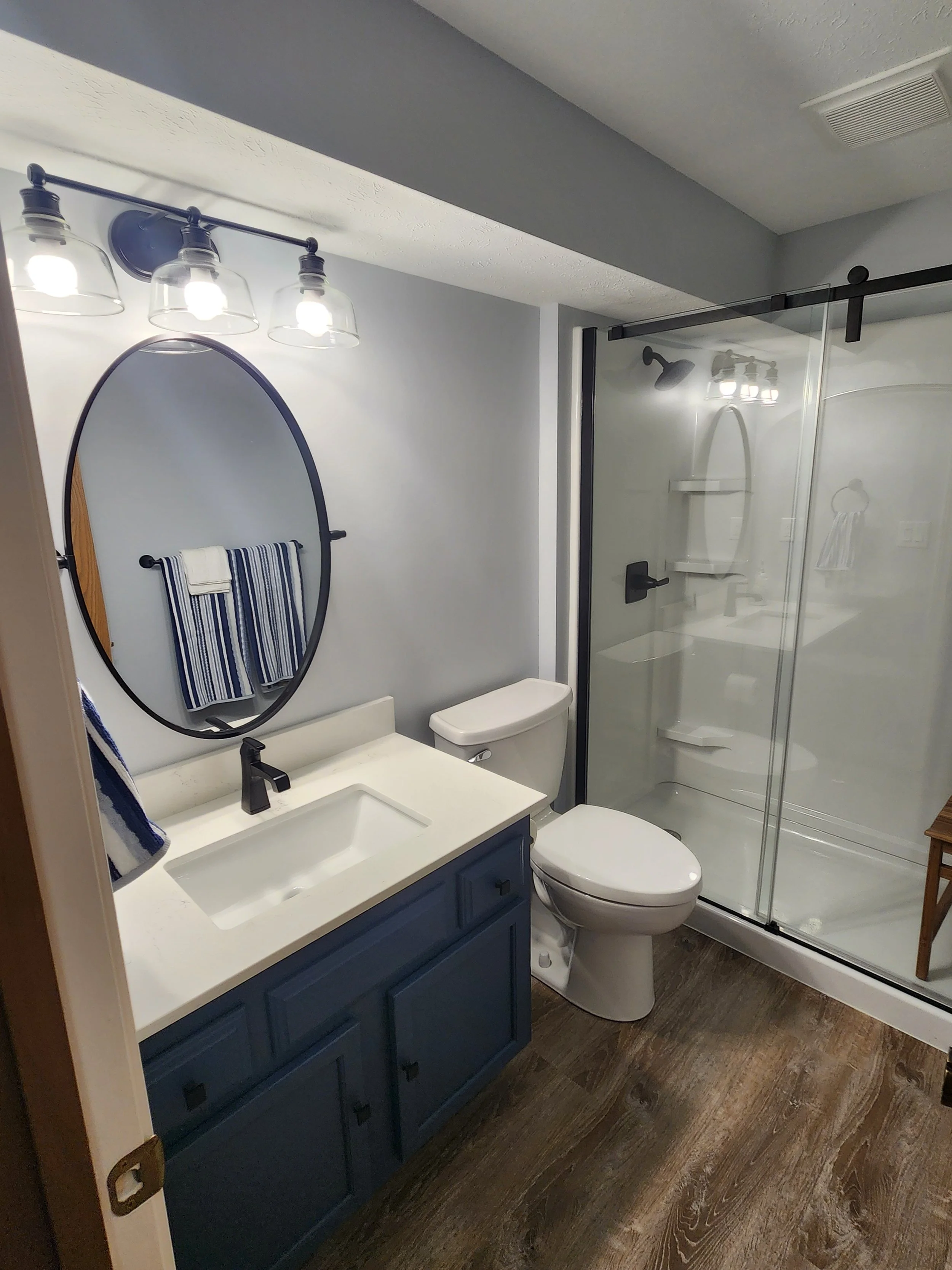 HM Remodeling full bathroom remodel featuring round mirror barn door and walk-in shower in South Bend Indiana