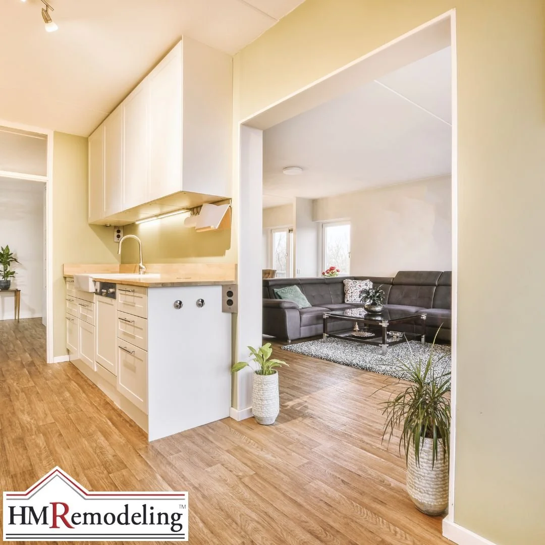 Open concept kitchen and living room remodel featuring white shaker cabinetry, butcher block countertop, wood-look luxury vinyl flooring, and neutral paint in a South Bend, Indiana home remodeled by HM Remodeling