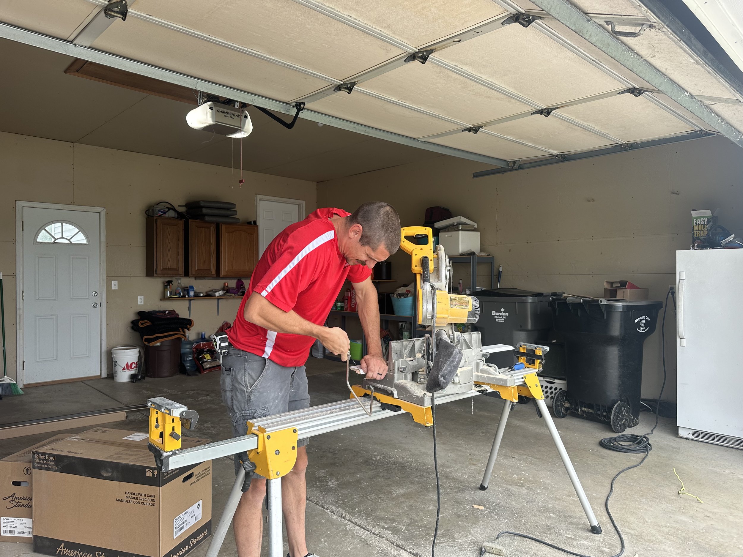 HM Remodeling technician in red uniform using miter saw during a home remodel in South Bend Indiana