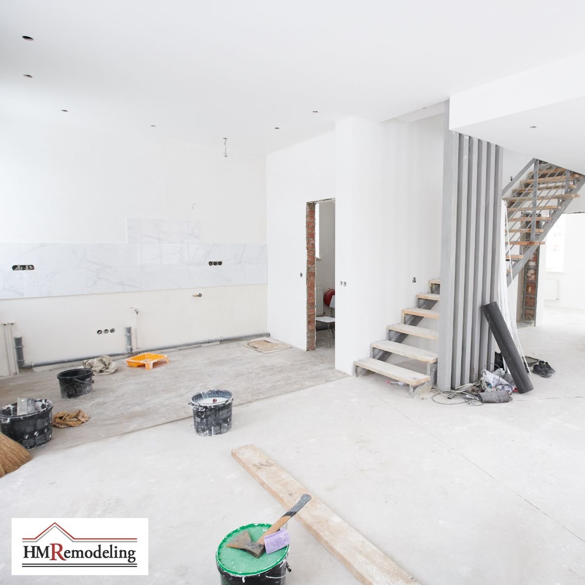 Basement finishing project in progress showing freshly drywalled open living area with recessed lighting rough-in, staircase framing, plumbing rough-in, and construction materials by HM Remodeling in South Bend, Indiana