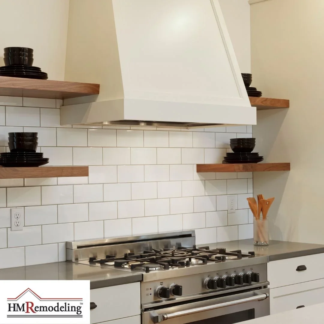 Remodeled kitchen featuring stainless steel range, white subway tile backsplash, custom range hood, open wood shelving, and white cabinetry by HM Remodeling in South Bend, Indiana