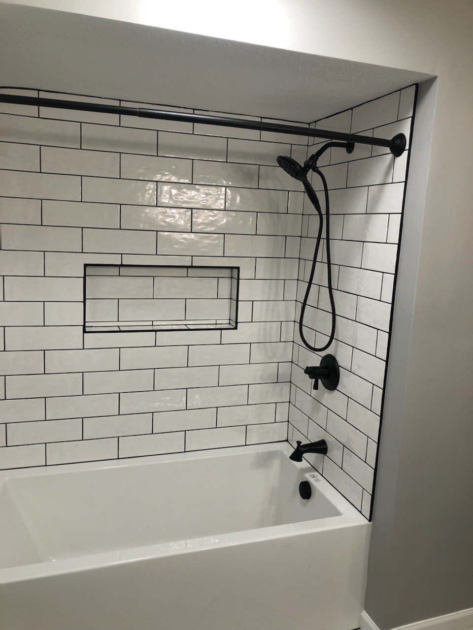 HM Remodeling white subway tile shower with black fixtures and niche in Granger Indiana