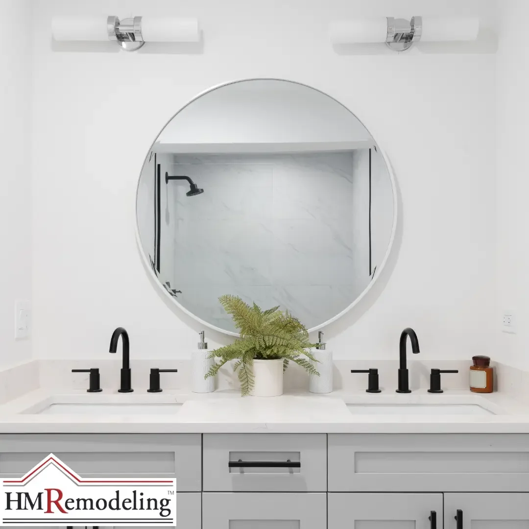 A bright bathroom with a gray double vanity, white quartz counters, a round mirror, and matte black faucets and hardware in a South Bend, Indiana home.
