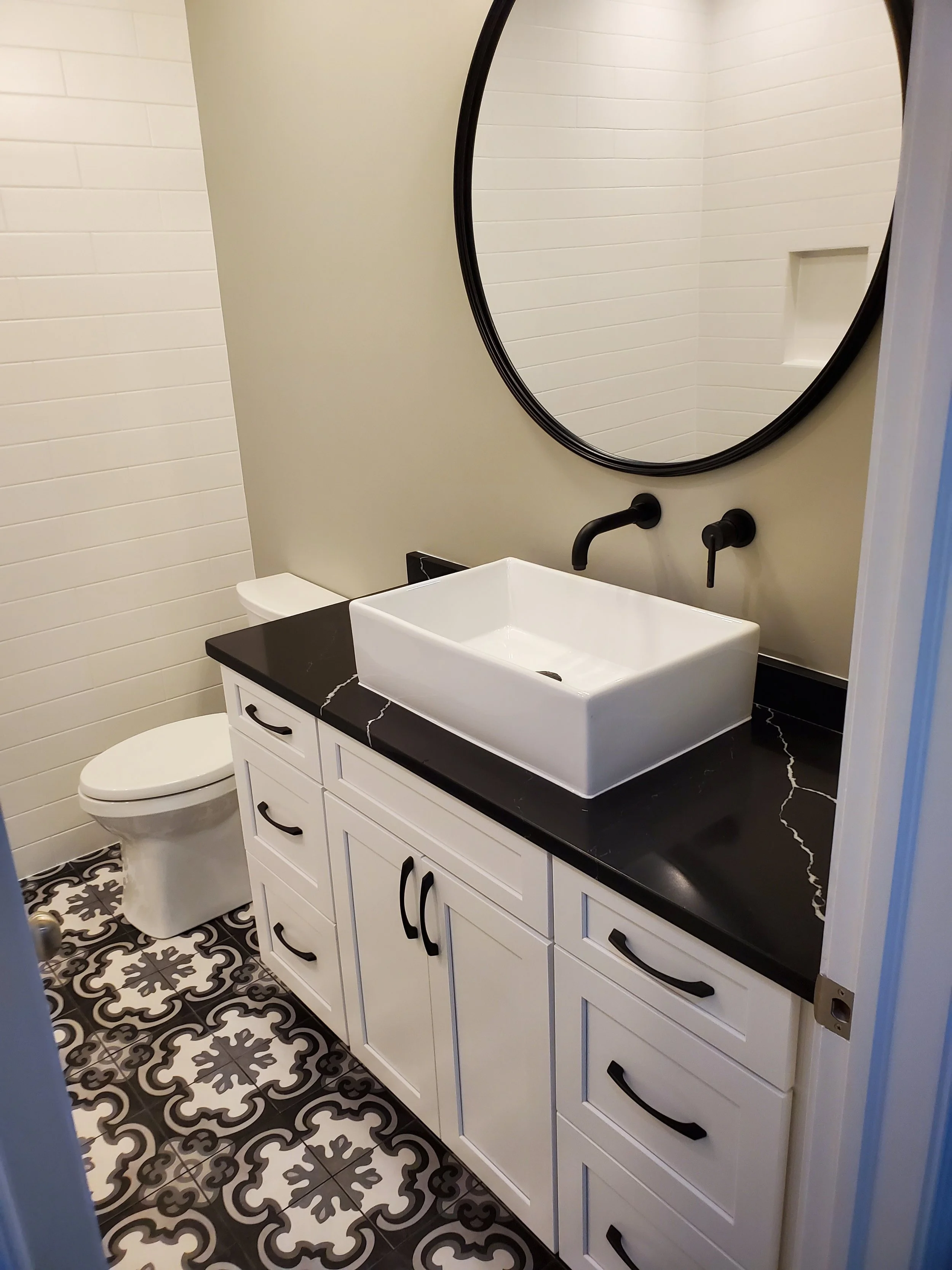HM Remodeling dramatic black tile bathroom remodel with vessel sink and round mirror in South Bend Indiana
