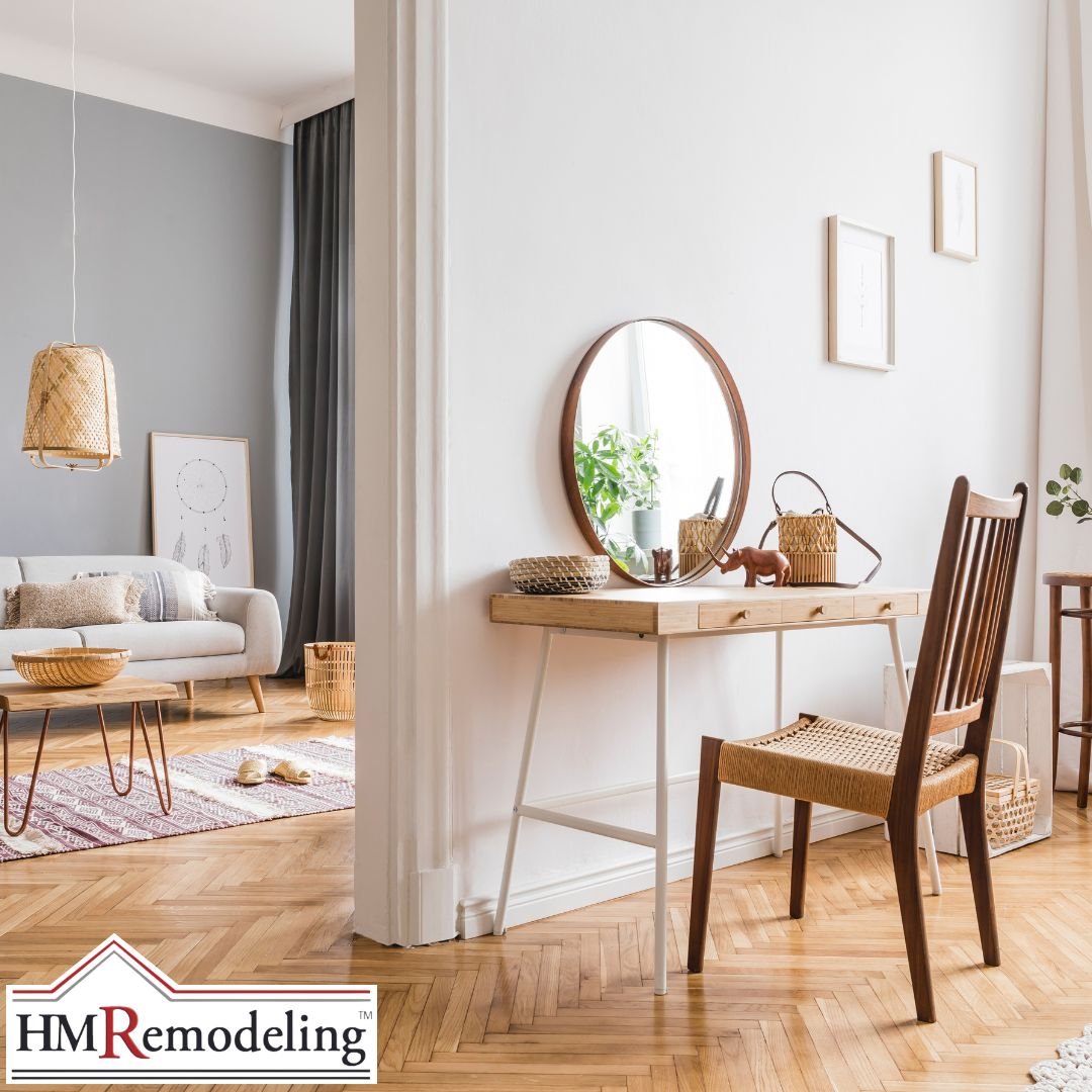 Bright open interior with herringbone hardwood floors, Scandinavian-style vanity desk, round wood-framed mirror, woven pendant light, and gray accent wall in a refreshed South Bend, Indiana home