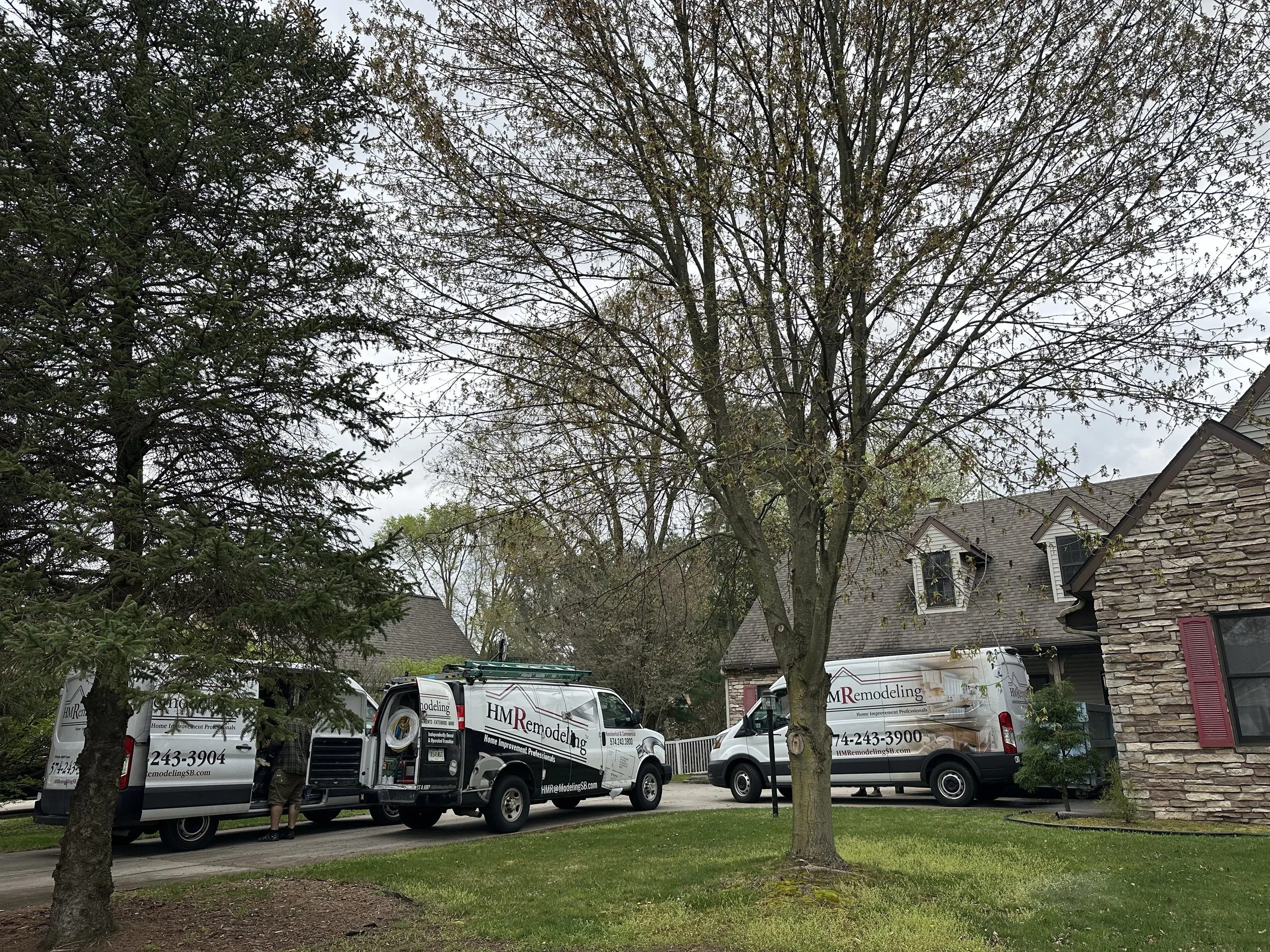 Three branded HM Remodeling vans parked at a client home in South Bend Indiana representing the company's full in-house crew and professional fleet