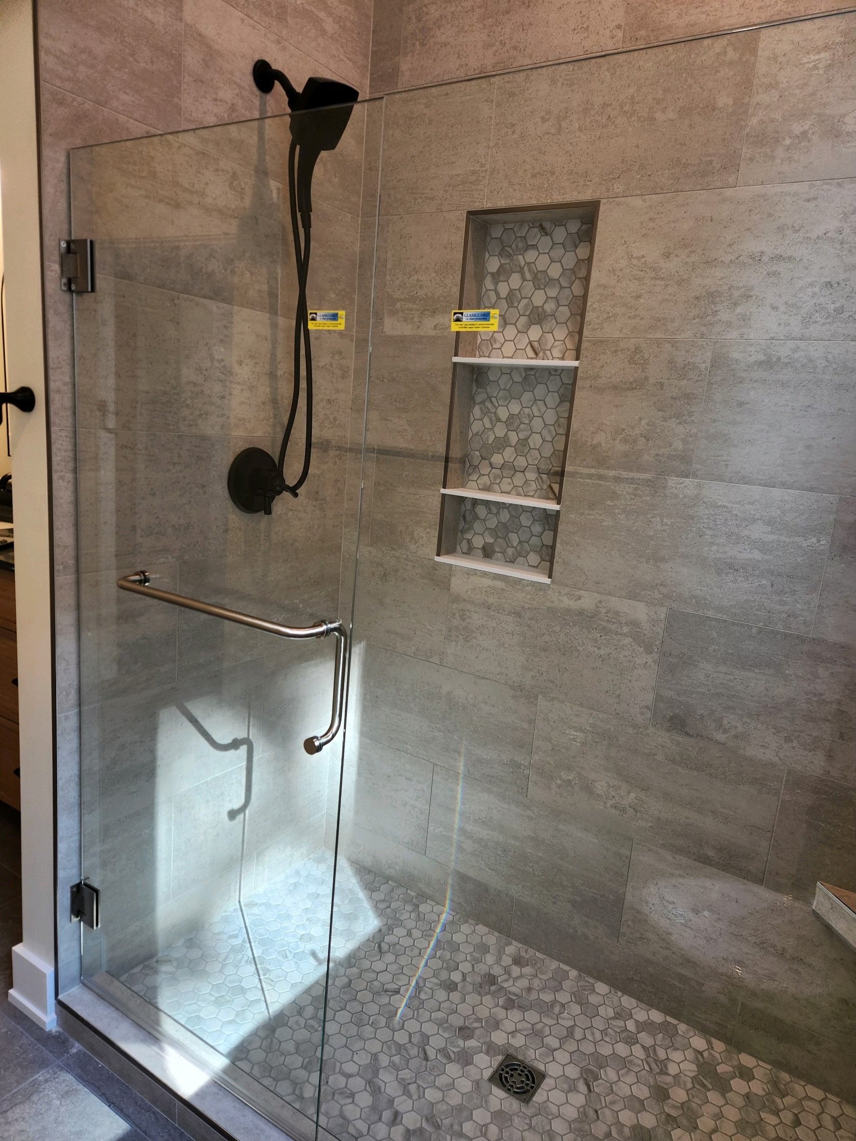 HM Remodeling large format tile shower with built-in niche and black fixtures in South Bend Indiana