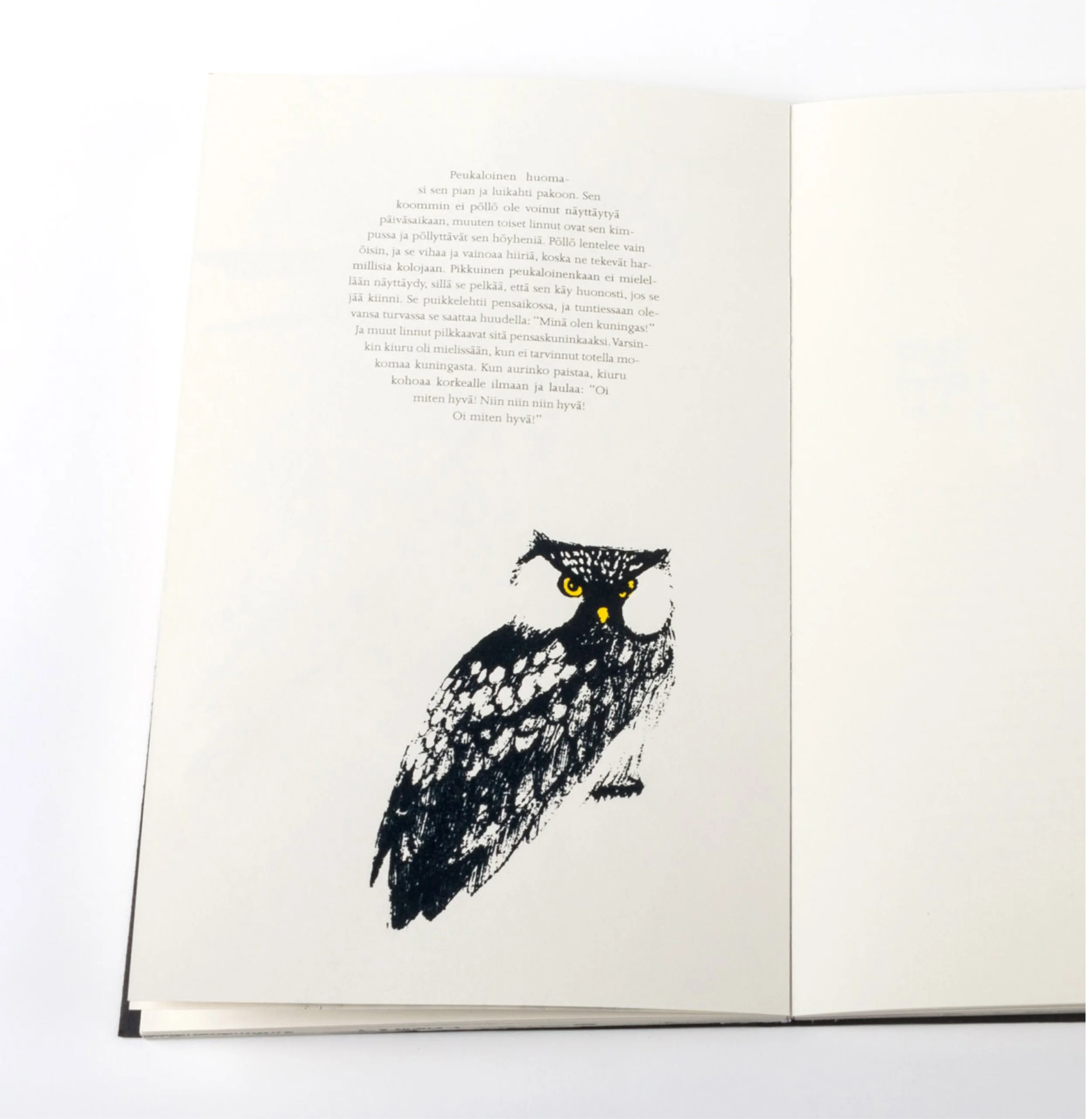 Open book showing a page of Finnish text and a black and yellow illustrated animal, possibly a cat.