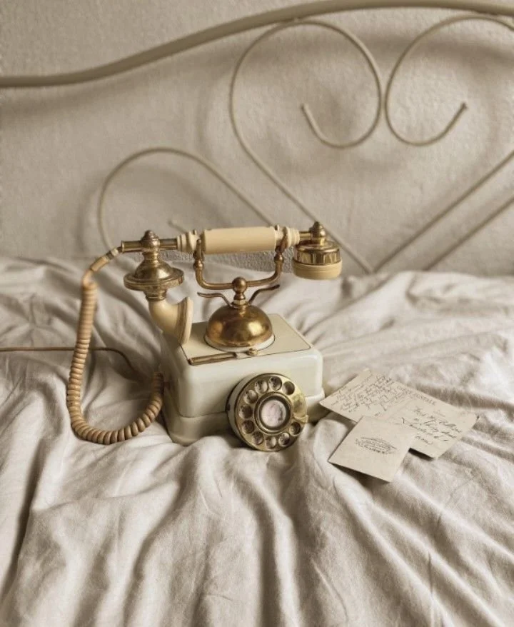Vintage telephone on a soft cream linen bed, styled in a warm, neutral interior setting