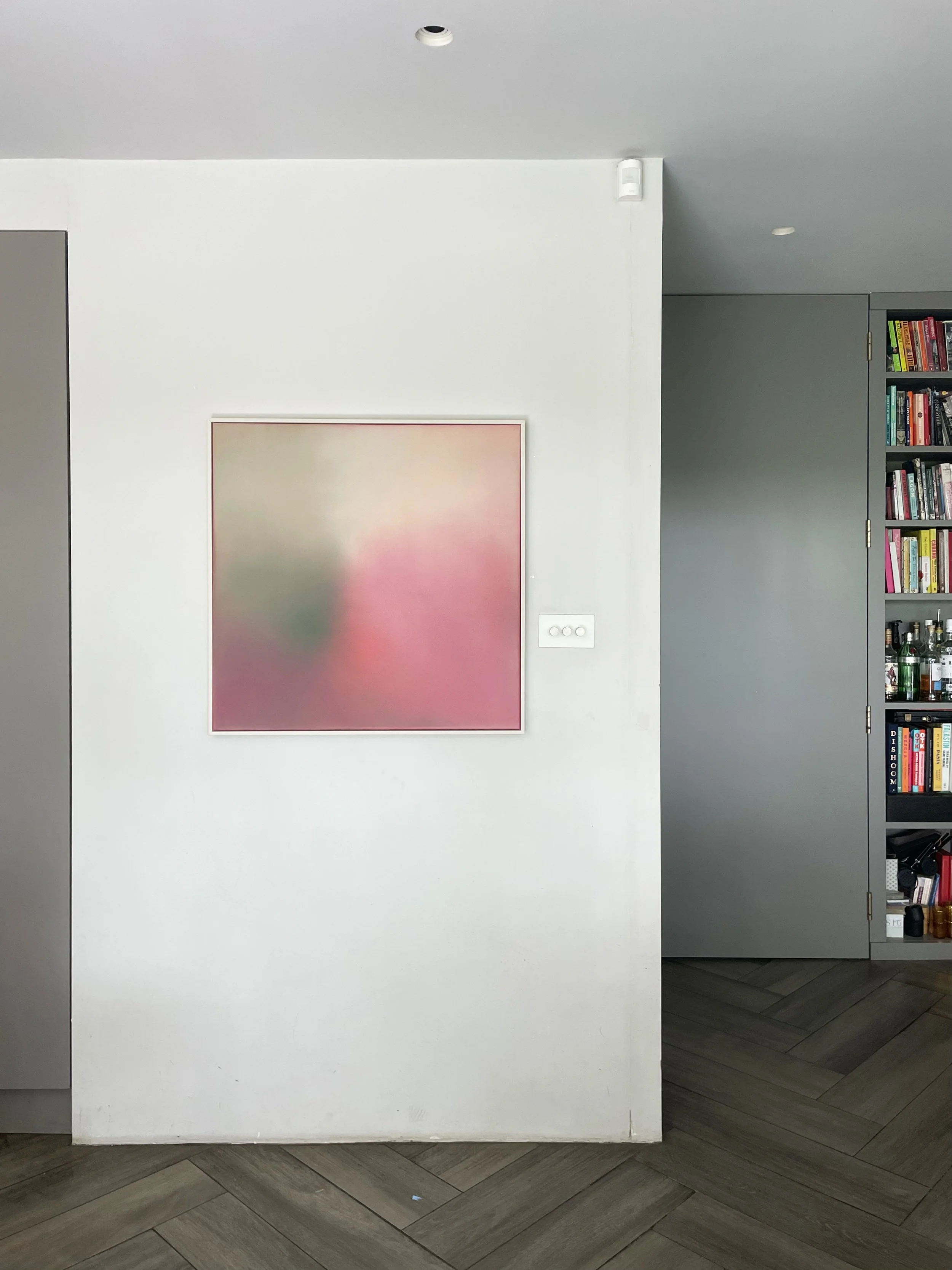 Minimalist abstract artwork with pink, green, and gray gradient, hung on a white wall in a modern interior space.