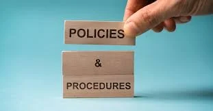 A hand stacking tiles labeled 'Policies' and 'Procedures' on a blue background.
