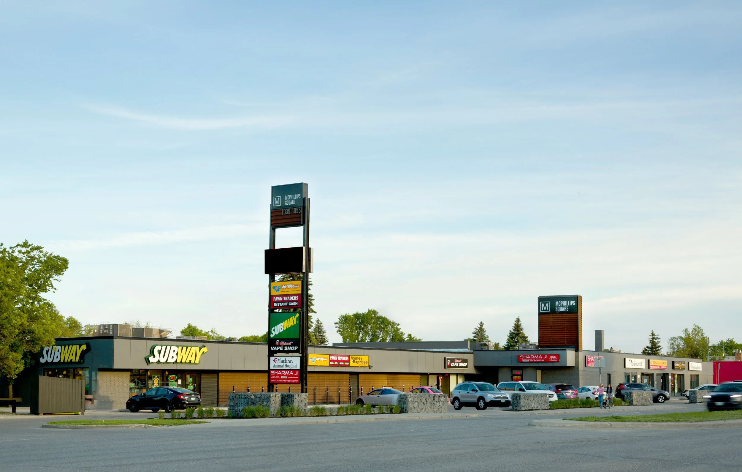 A shopping center with Subway restaurant, parking lot, and various signs including Subway, pawn shop, vape shop, and other businesses.