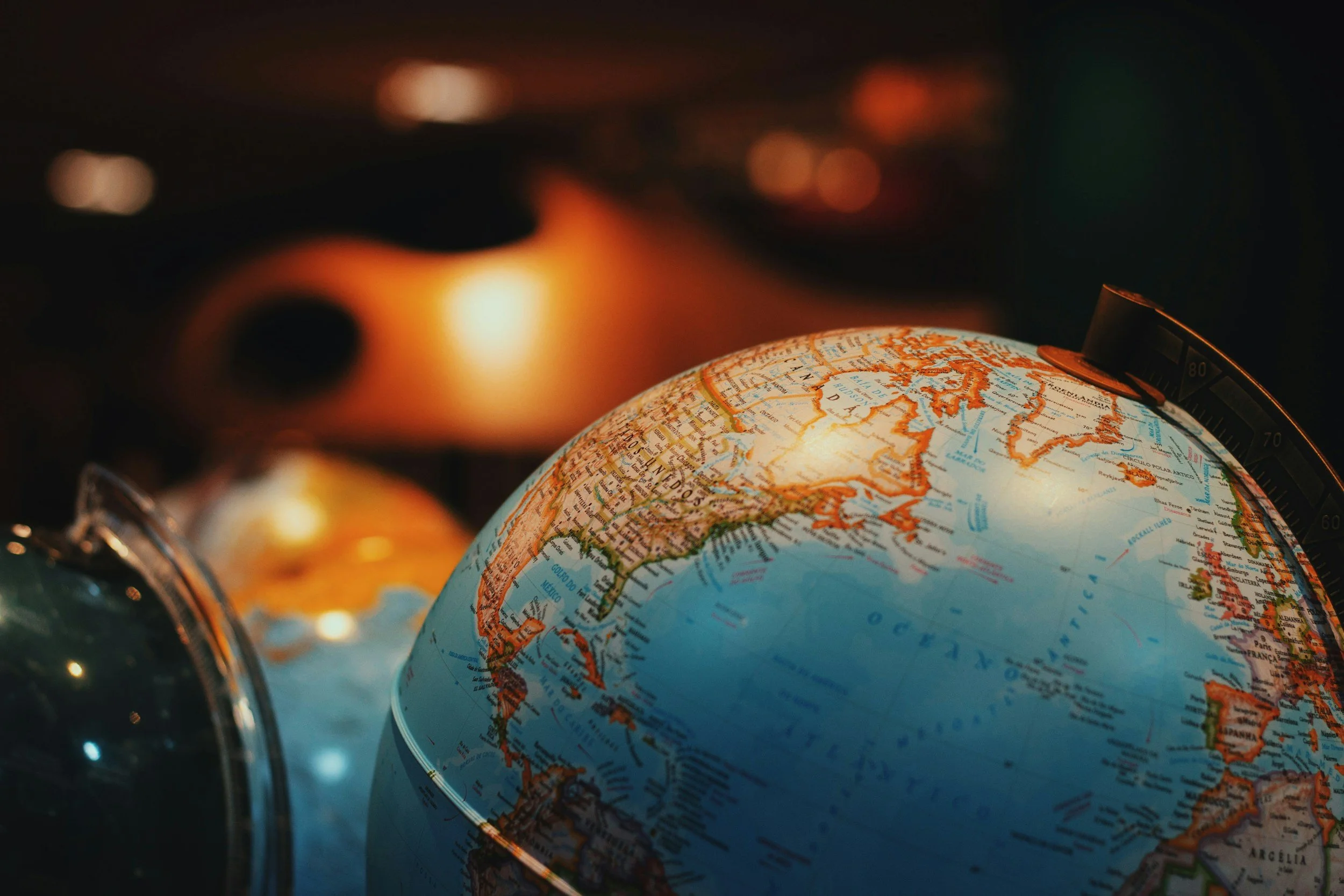 Close-up of a globe showing South America, with blurred background and orange lighting.