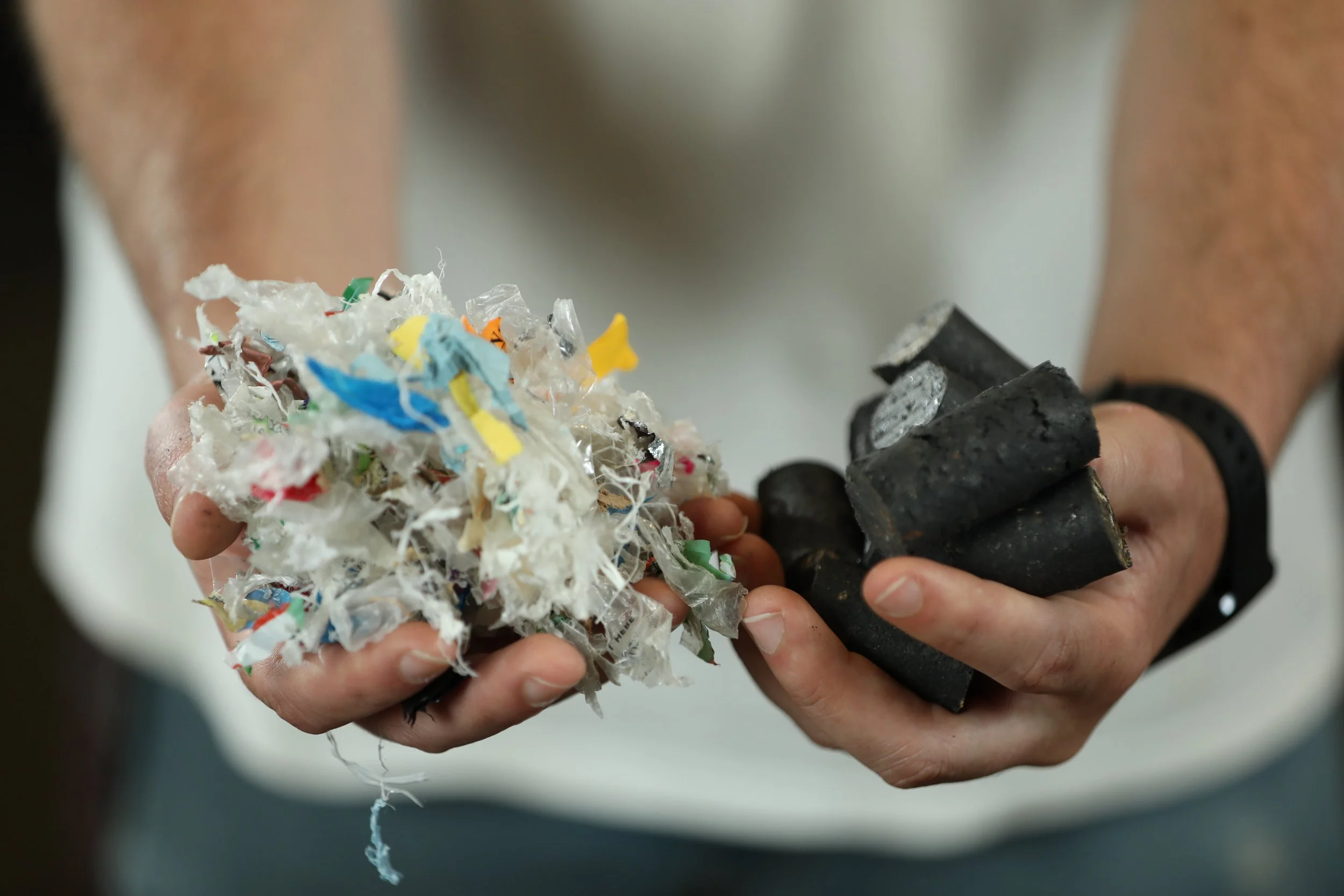 Person holding piles of shredded plastic and burnt rubber.