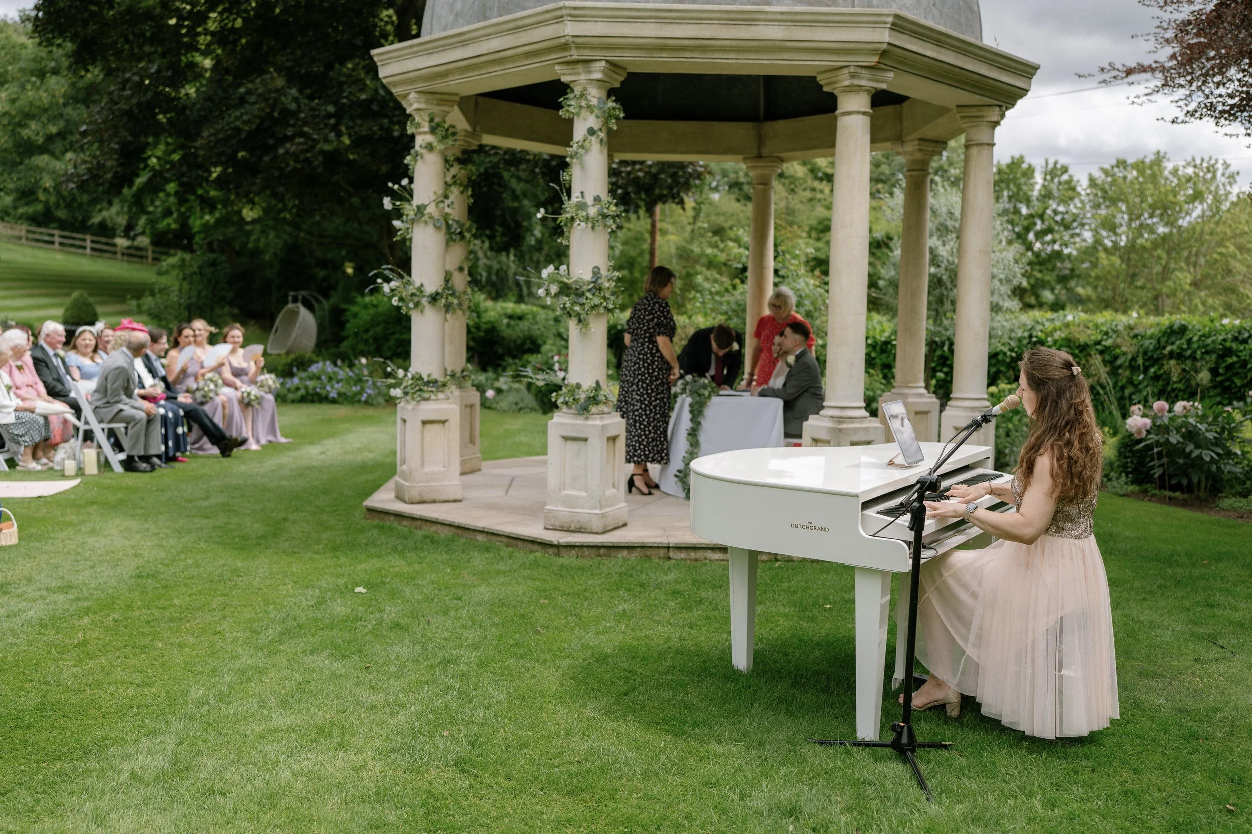 Kim Brooklyn speelt piano en zingt tijdens een huwelijksceremonie in de tuin