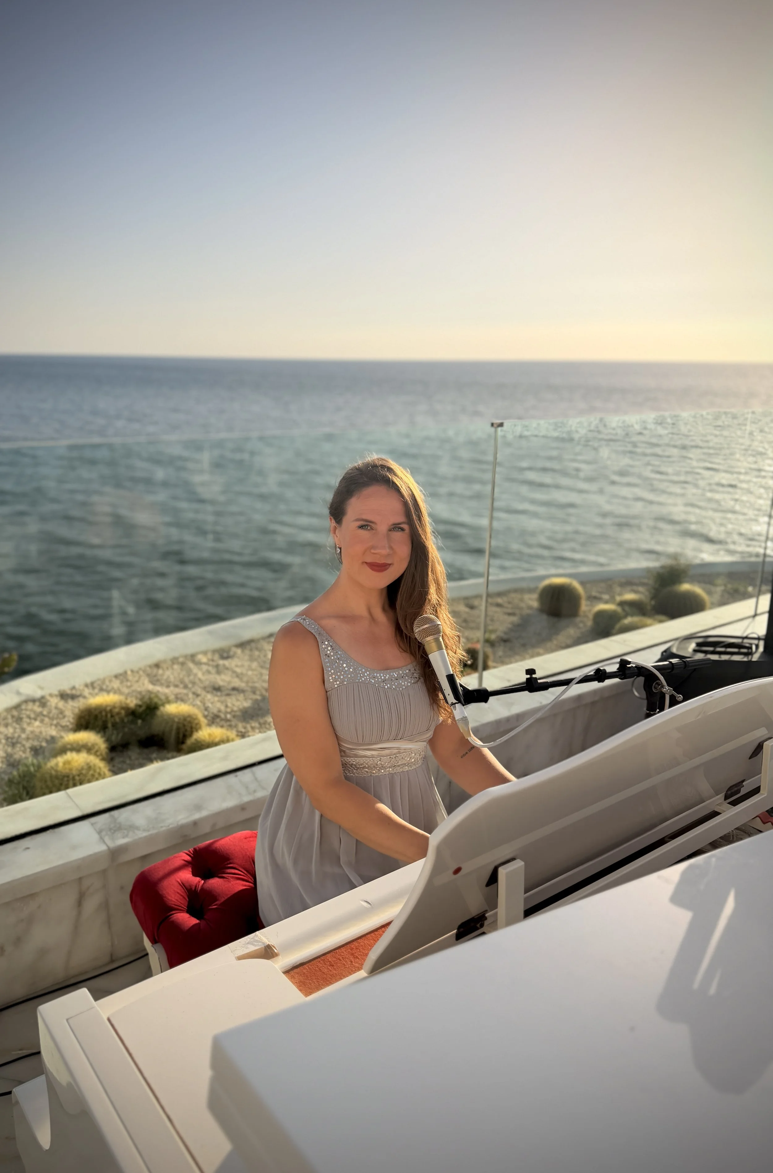 Kim Brooklyn performing at a white grand piano overlooking the sea at Le Mirage in Tangier, Morocco