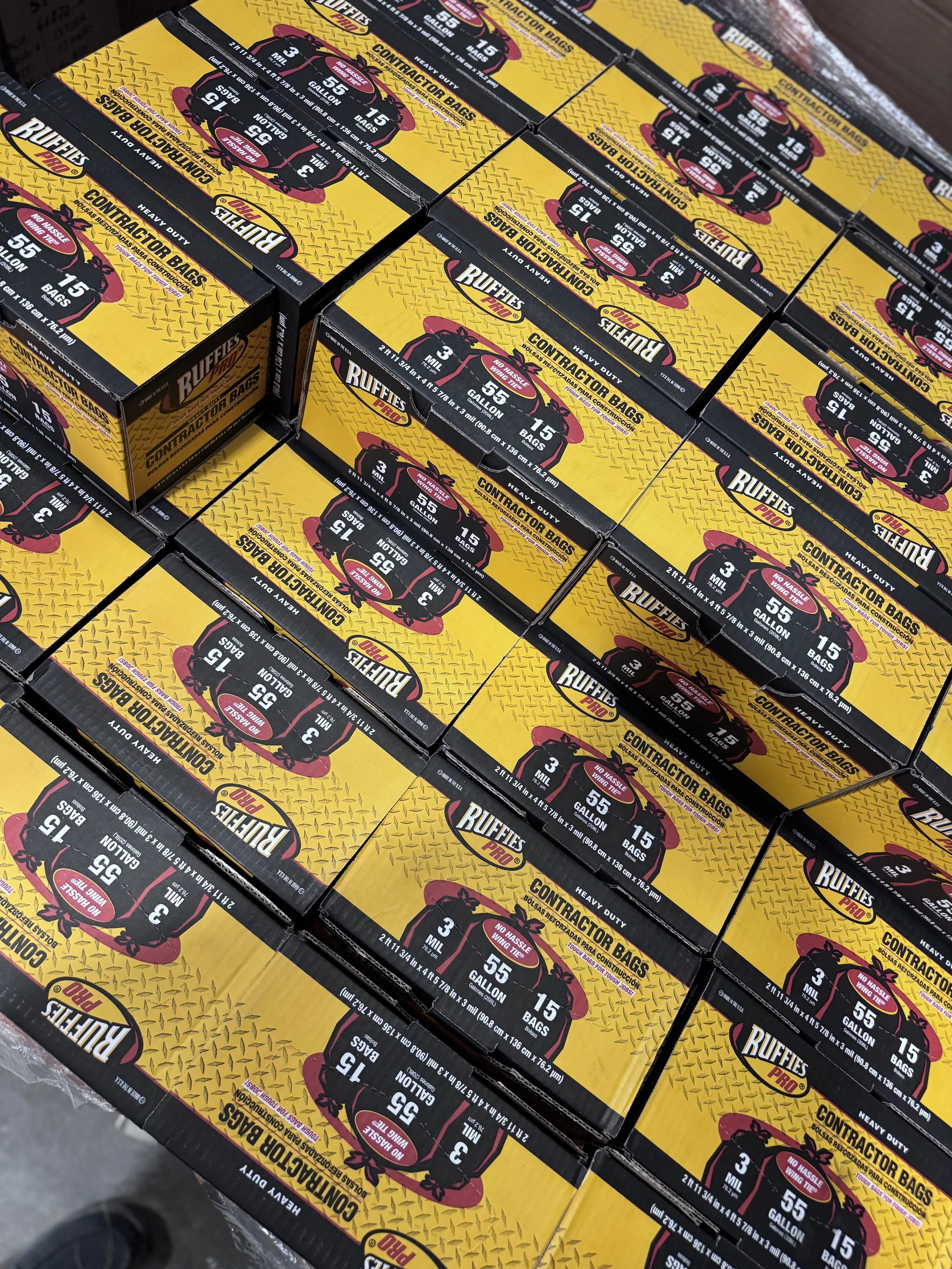 Boxes of RUFFIES Pro heavy-duty contractor bags, 55-gallon size, 15 bags per box, stacked on a store pallet.