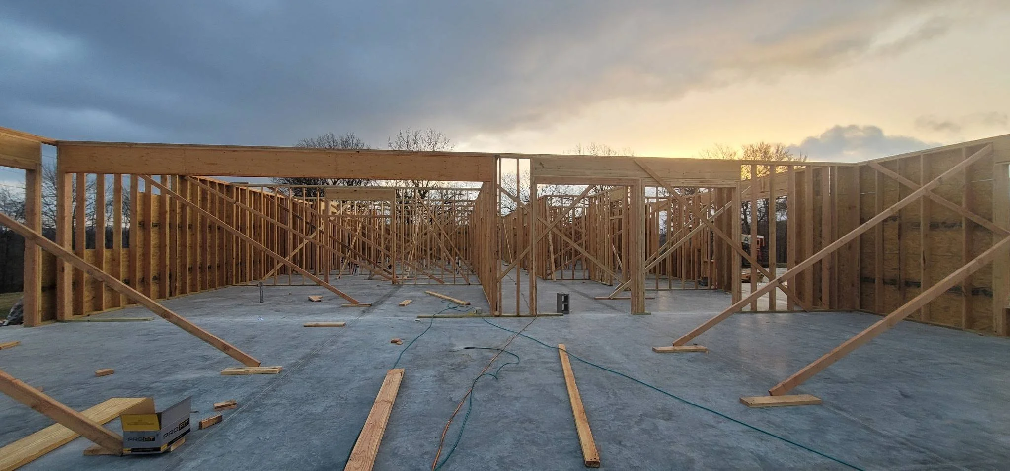 Wooden framing construction of a building under a cloudy sky.