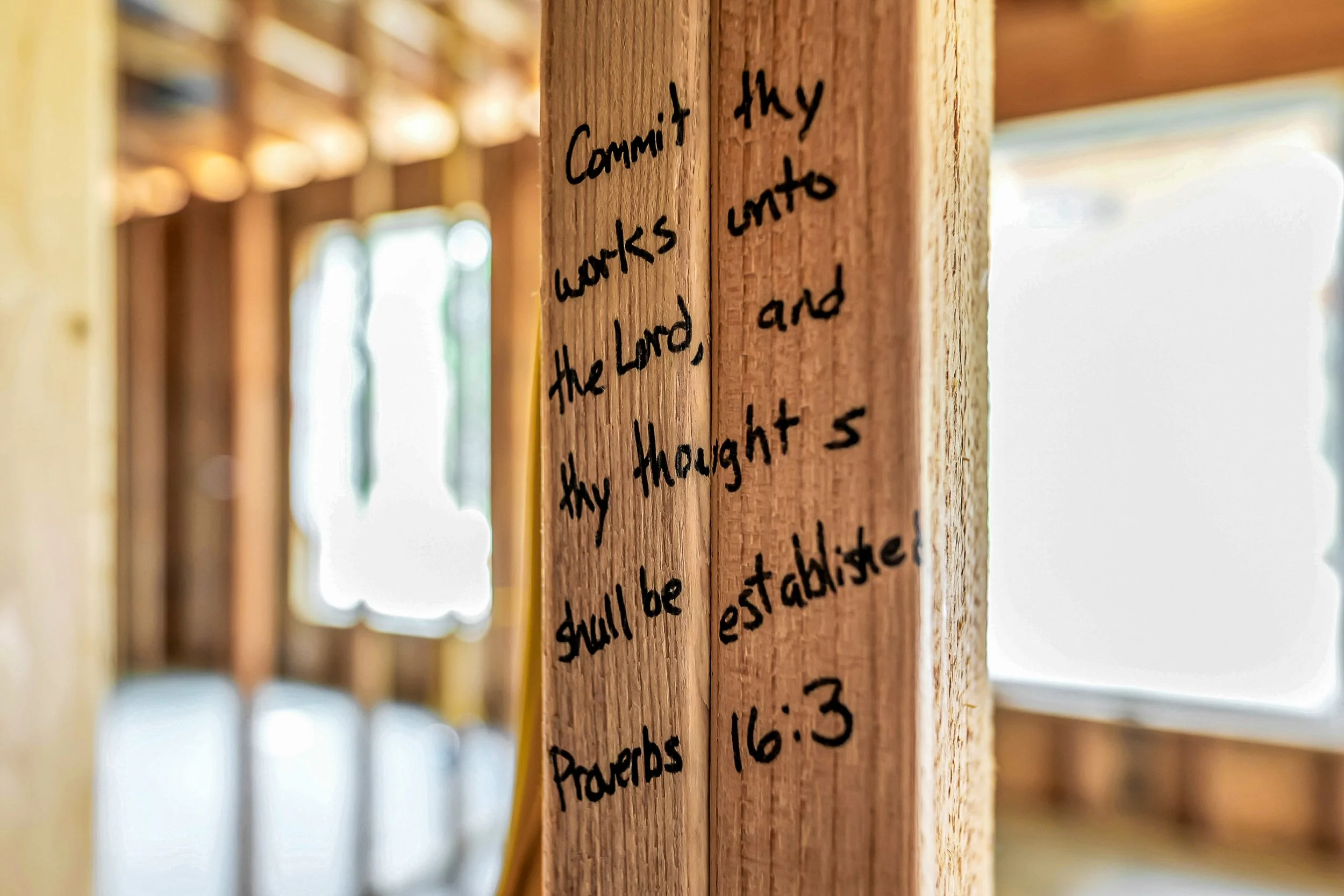Wooden beams with handwritten notes, with sunlight shining through windows in the background.