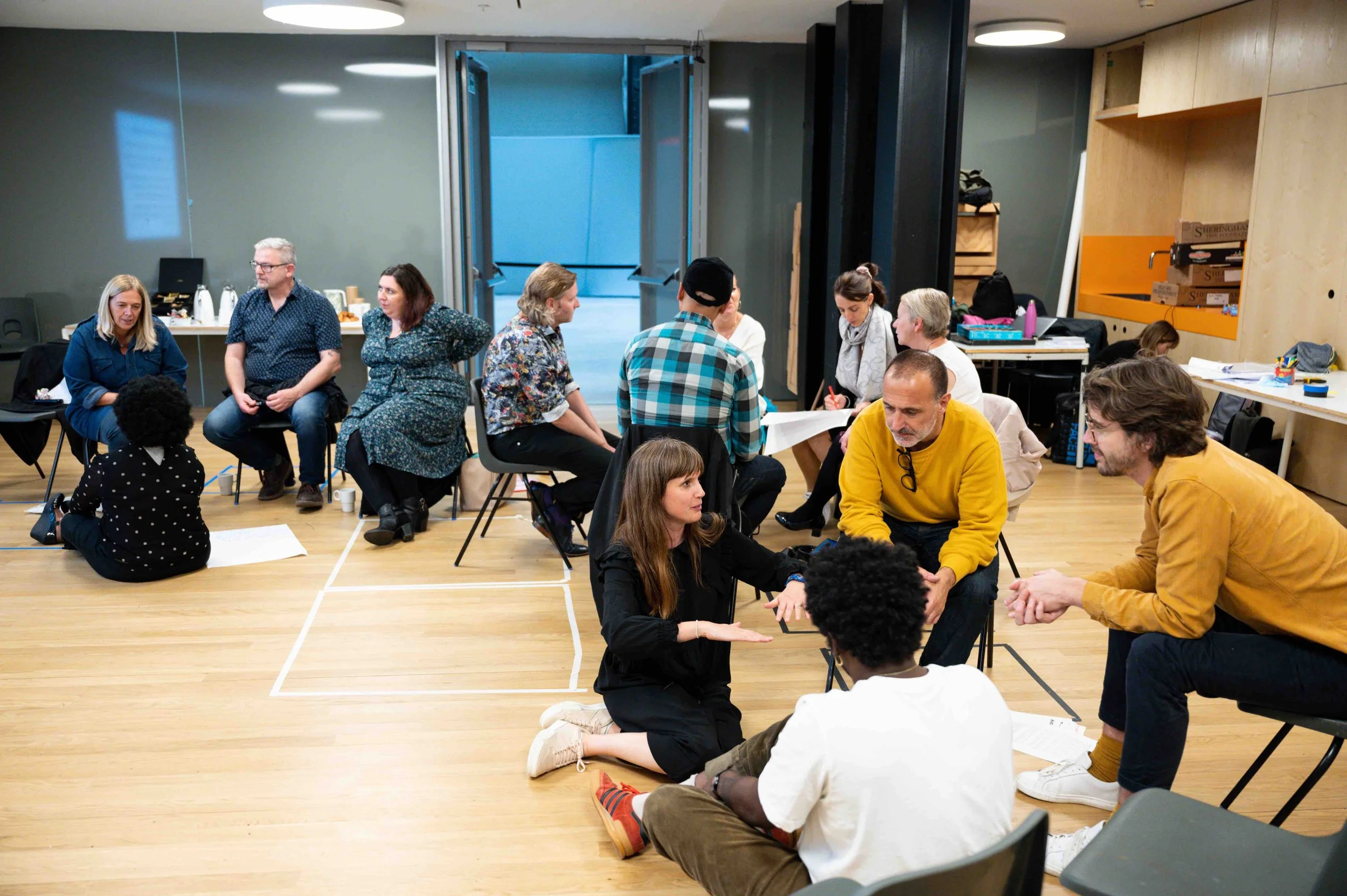 Group of adults sitting in workshop situation in small groups conversations.
