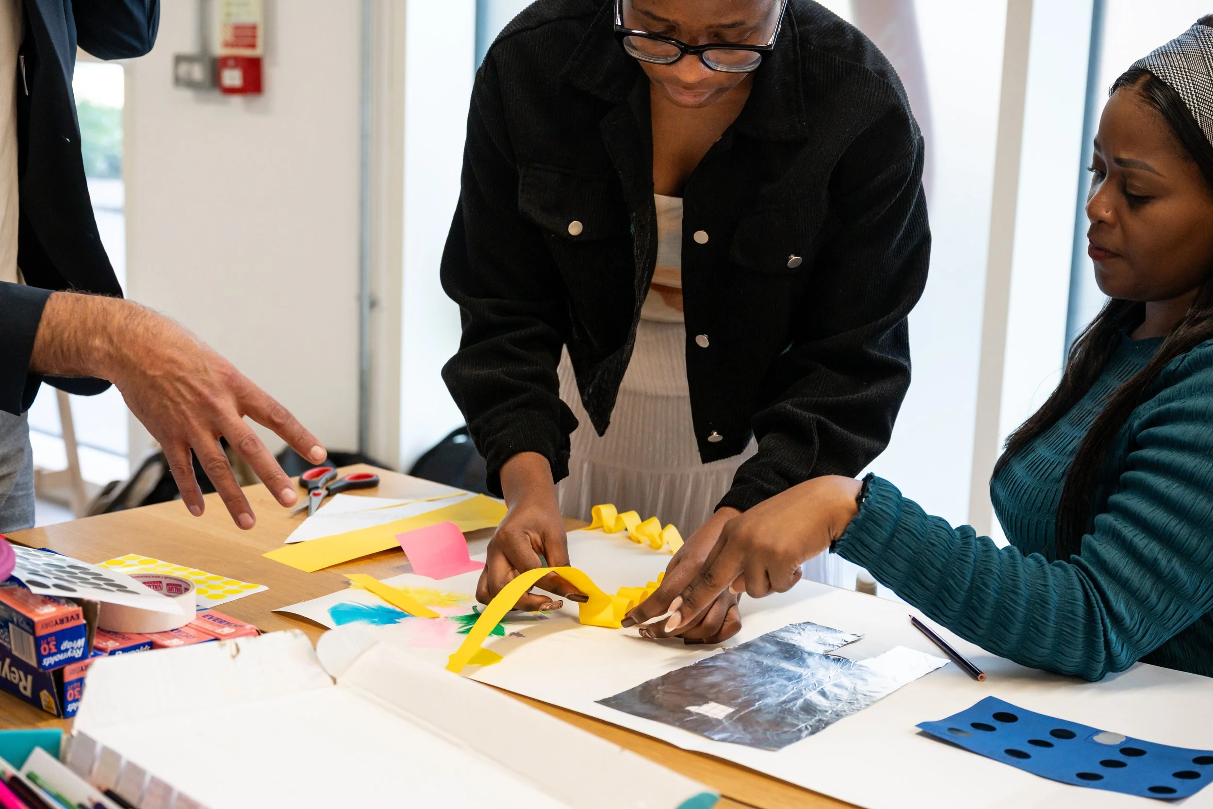 One adult woman arranges folded yellow paper over an image.