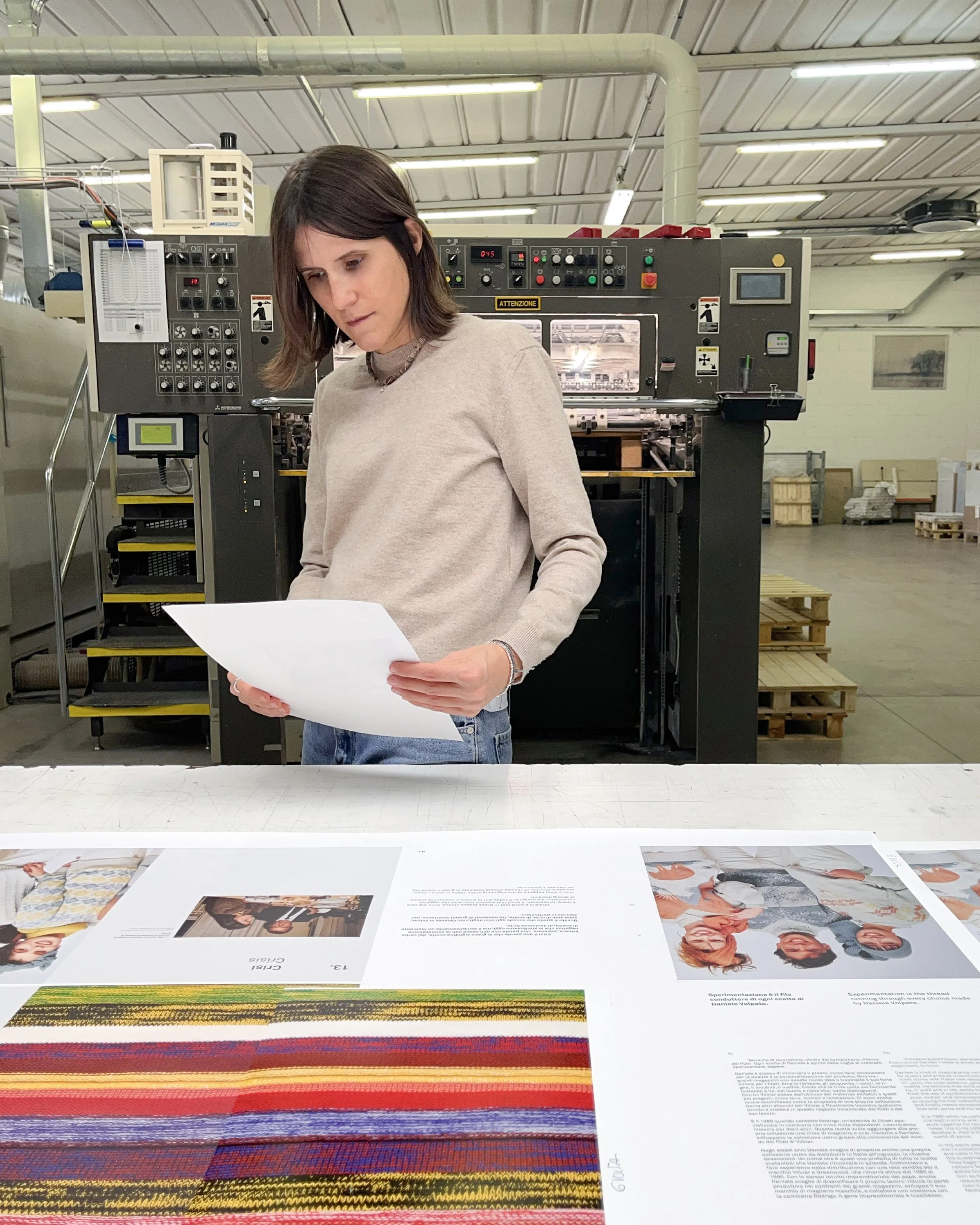 Avviamento stampa di un libro. Donna appare mentre tiene in mano un foglio di prova e controlla la qualità della stampa del libro.