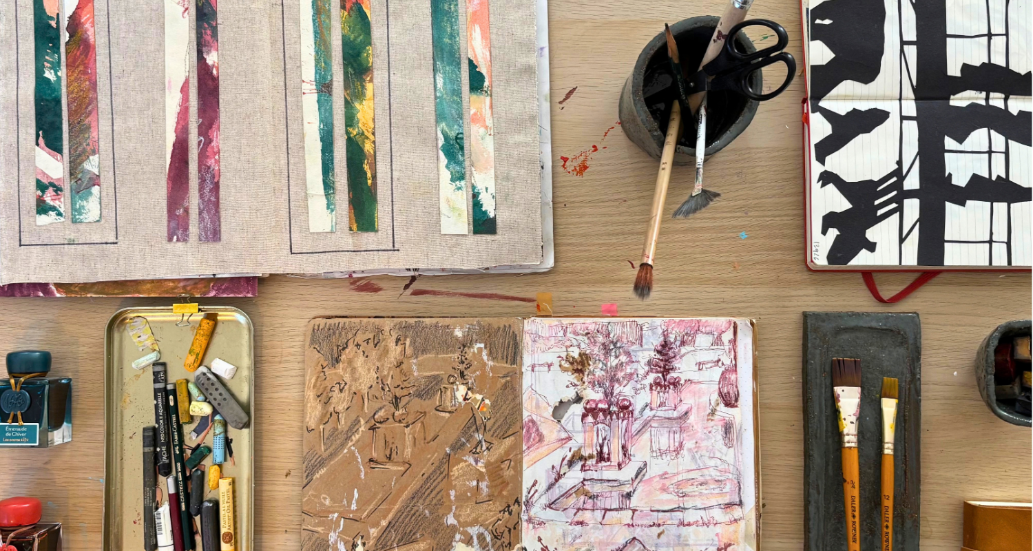 Overhead view of Anastasija Sarajeva’s studio table with observational interior drawings, painted collage strips and black paper cutouts, surrounded by brushes, crayons and inks.