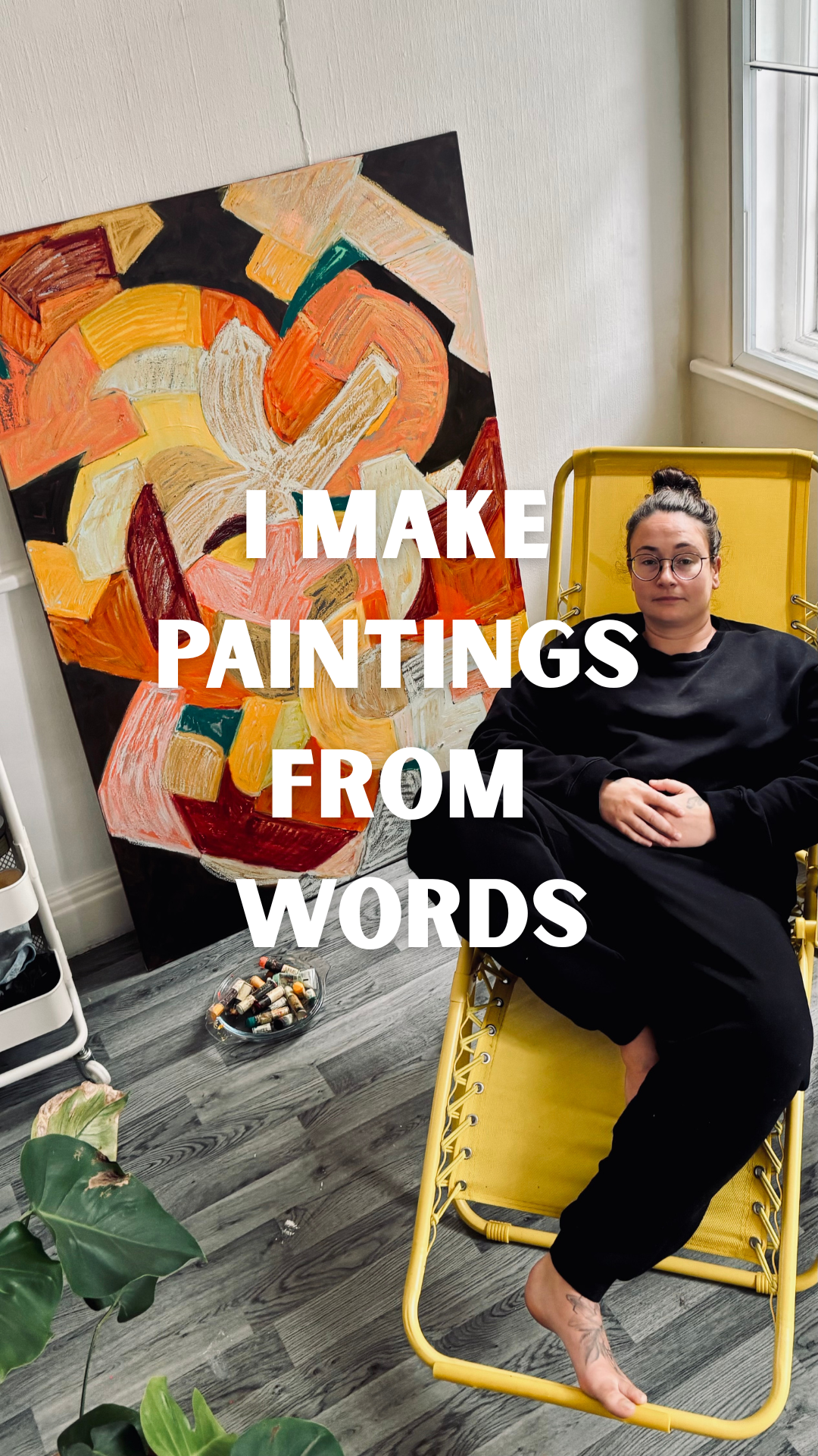 London abstract artist Anastasija Sarajeva seated beside a large orange, yellow and cream letterform painting in her studio. Text reads: “I make paintings from words.”