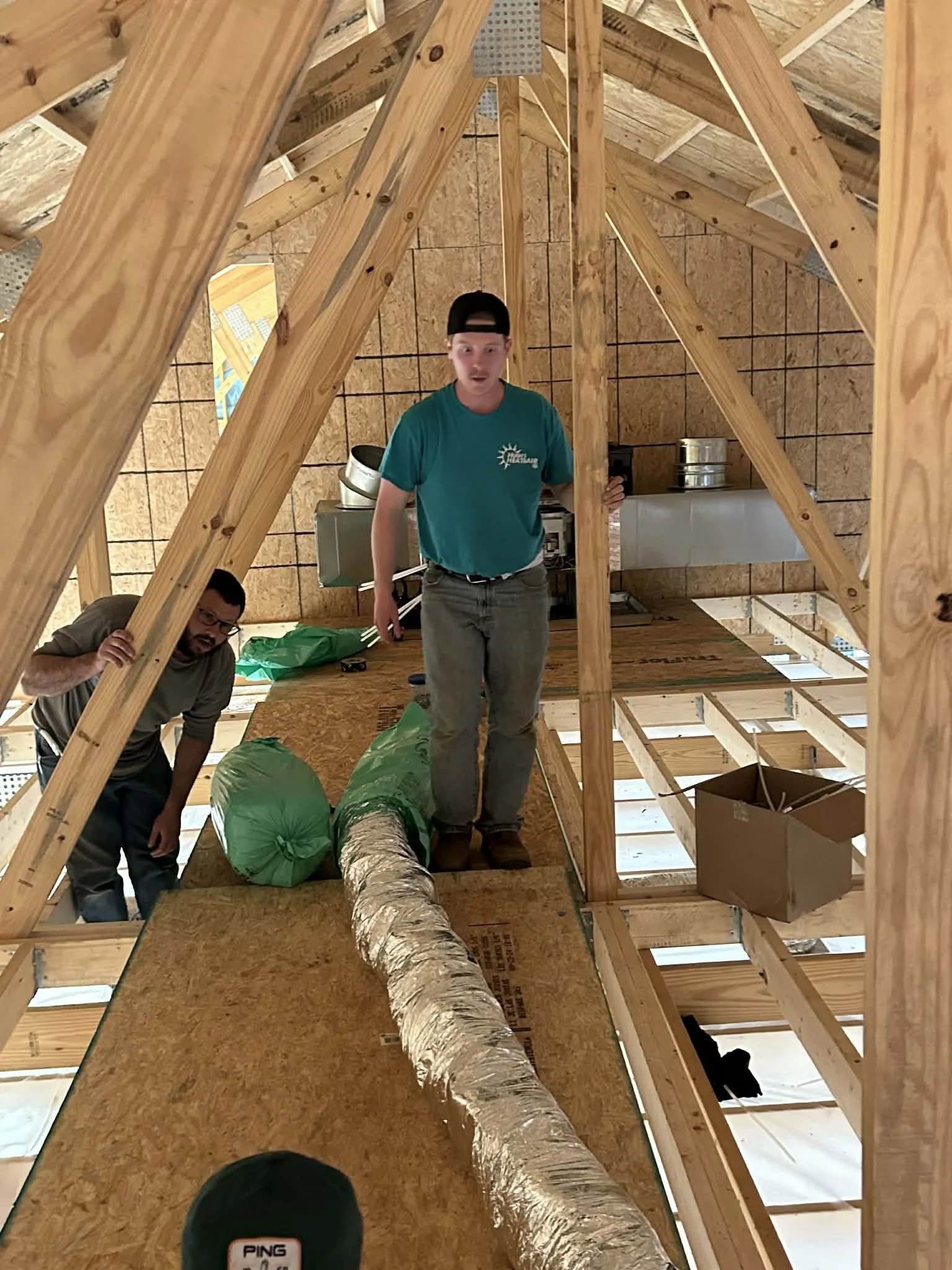 Heat and air technicians working on installation in a new house build