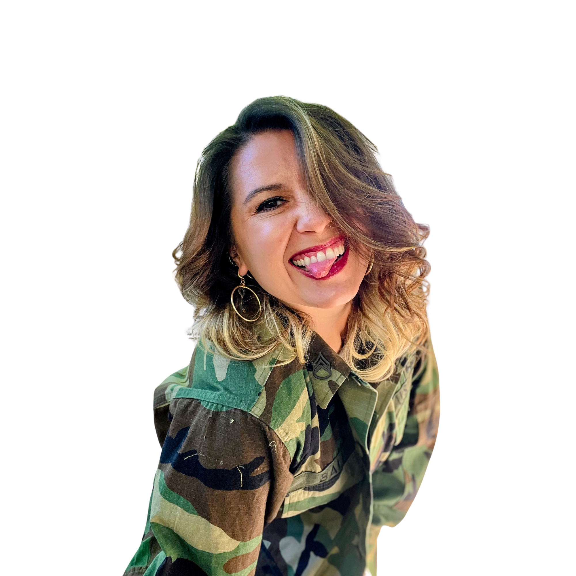 A woman with shoulder-length curly hair, wearing a camouflage jacket, making a playful face with her tongue sticking out and smiling, with black background.