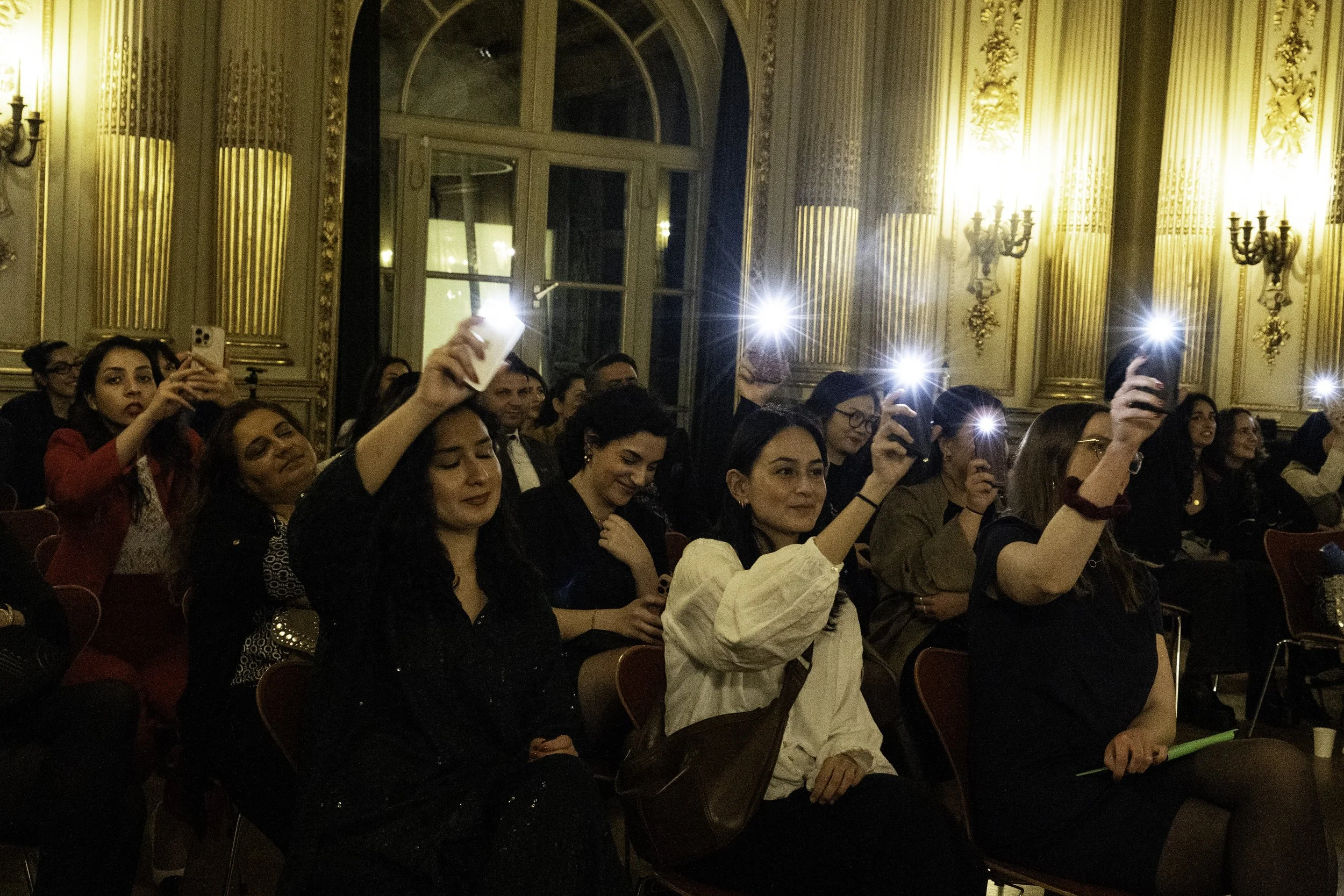 Menschen in einem eleganten Saal, die Fotos mit ihren Handys machen, während eines Events oder einer Gala.