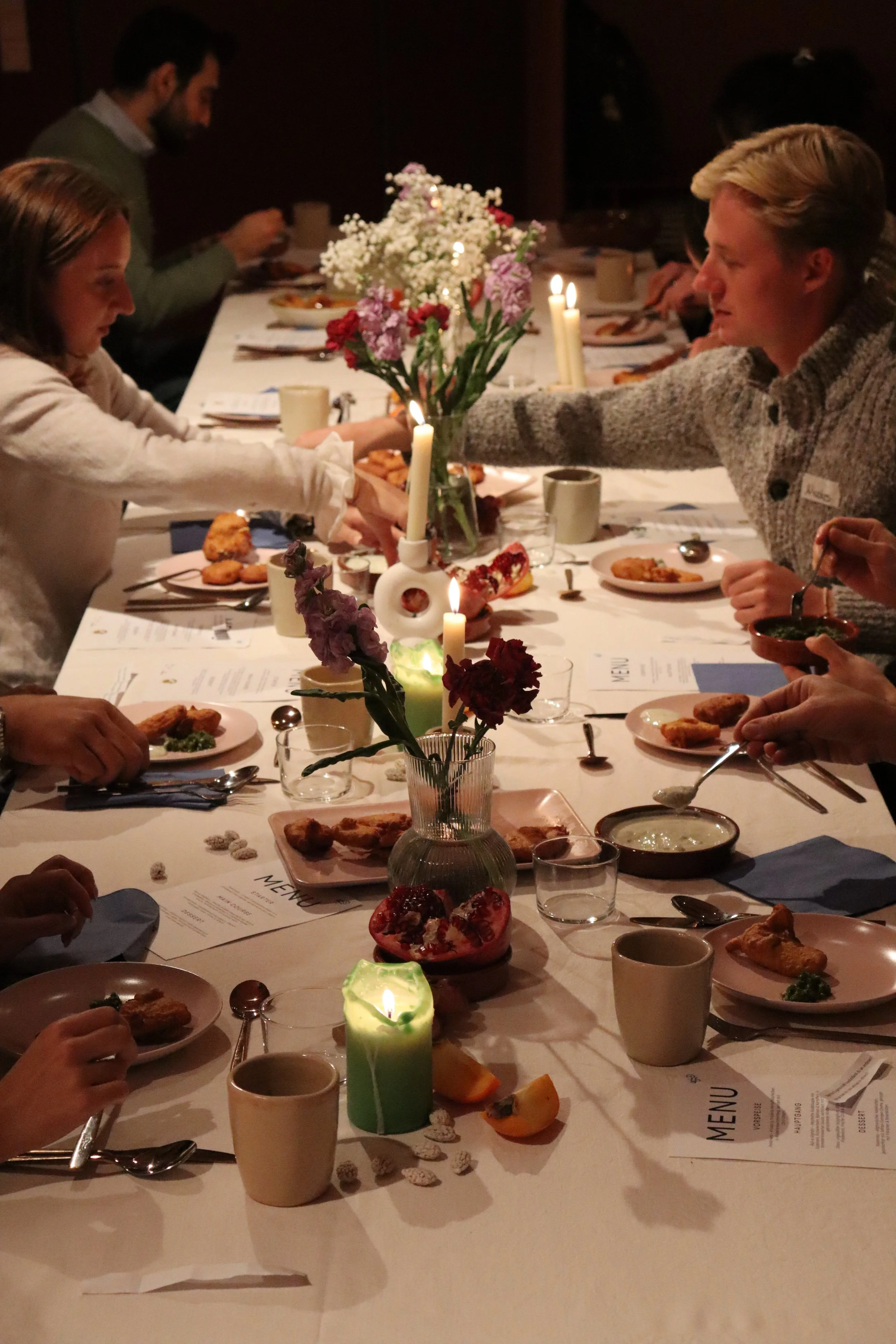 Familienabendessen an einem festlich gedeckten Tisch mit Blumen, Kerzen und Speisen in einer gemütlichen Umgebung.