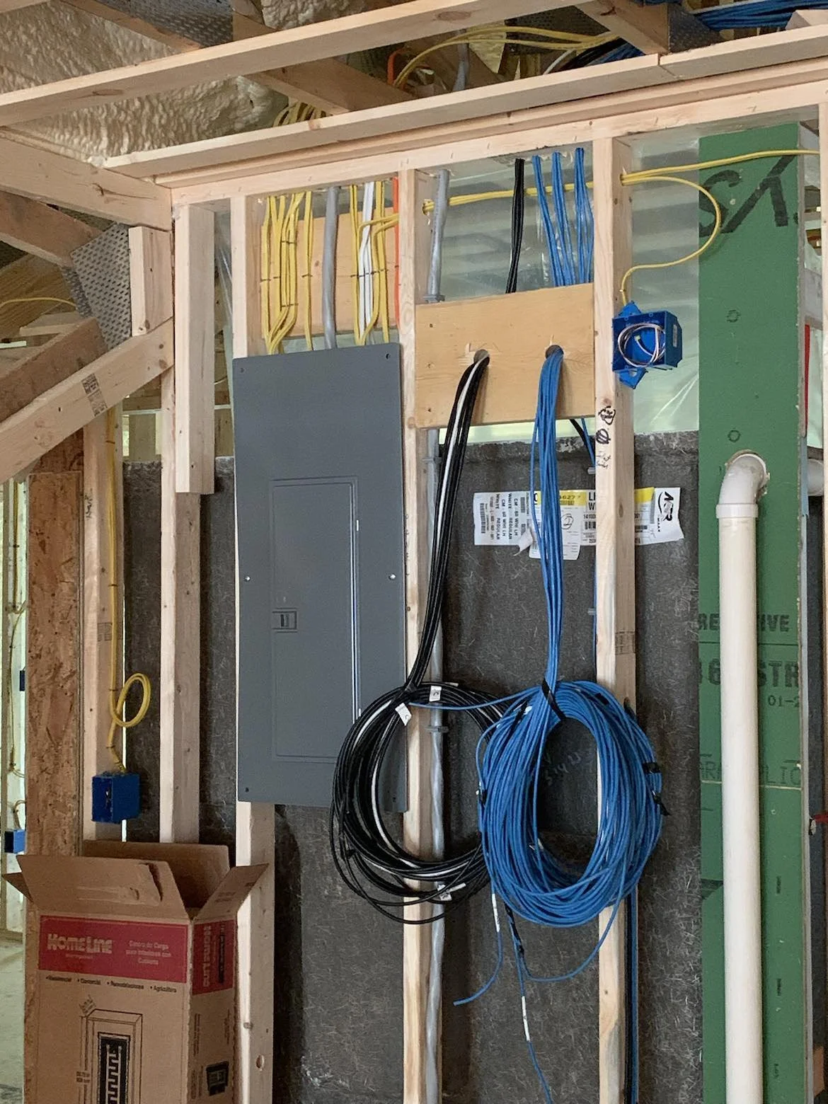 Construction wall framing with electrical wiring, boxes, and conduit in progress.