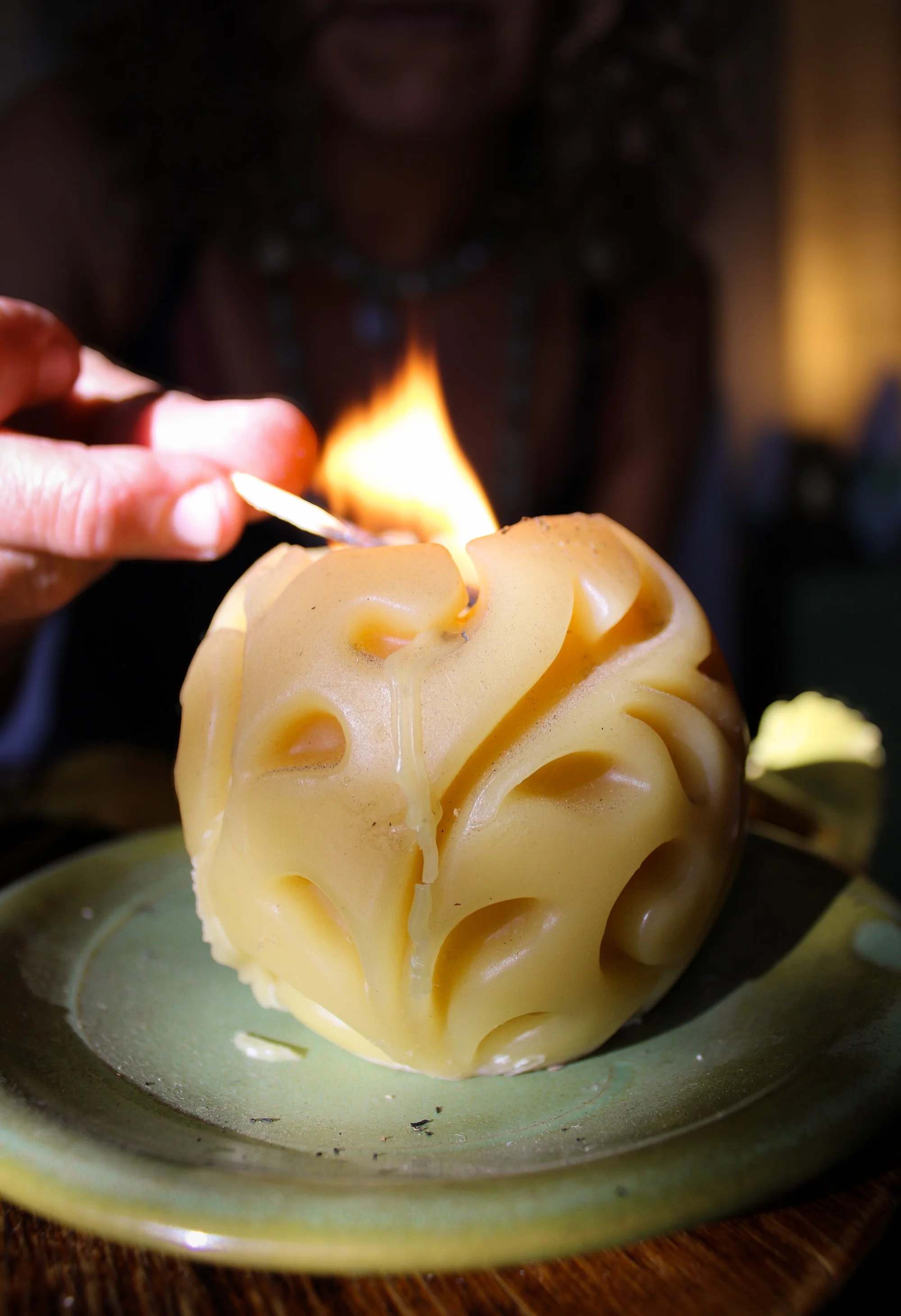A person lighting a scented candle shaped like a brain with a match.