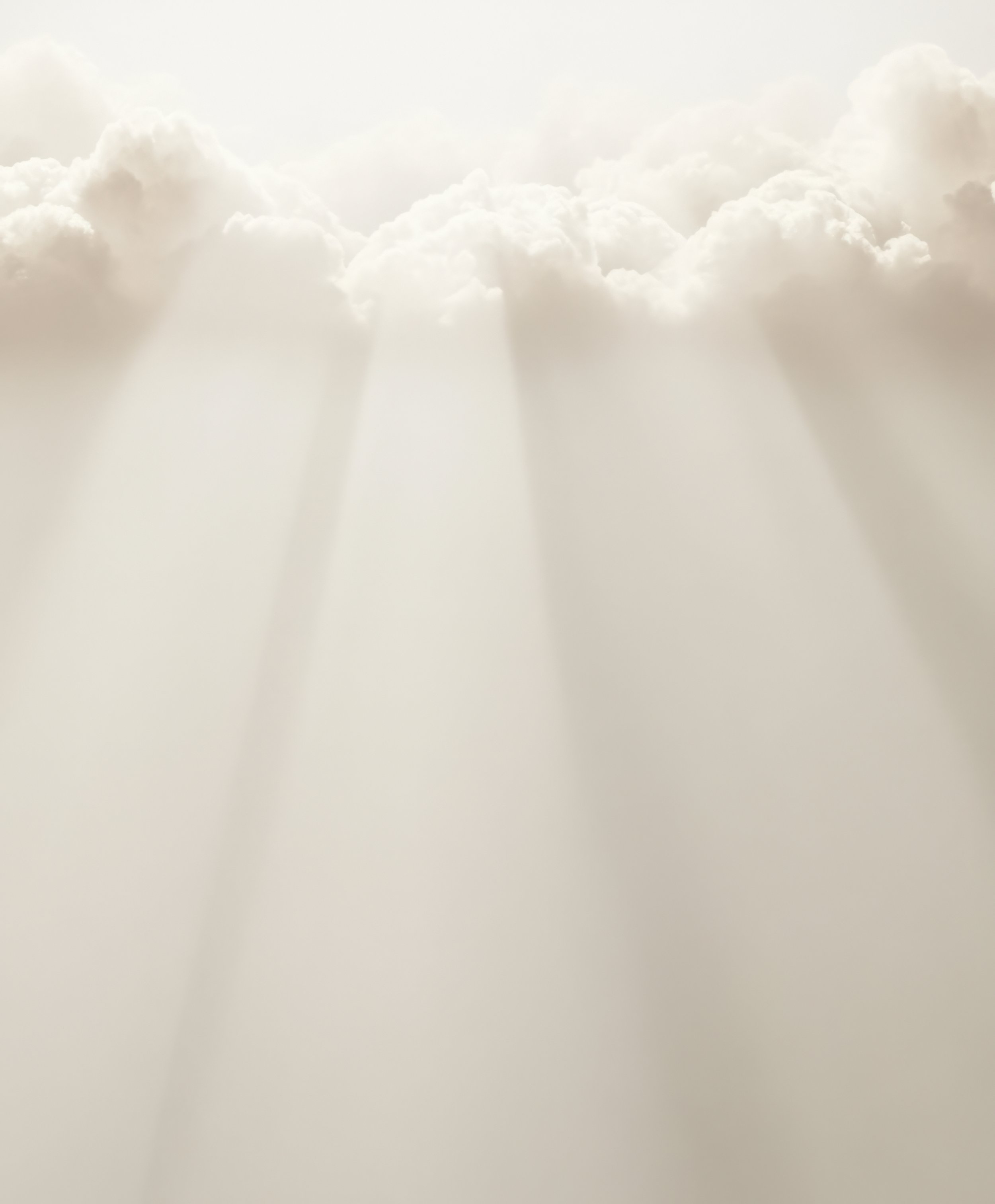 A view of soft, fluffy clouds in a light sky with sunlight streaming through, creating a serene and peaceful scene.