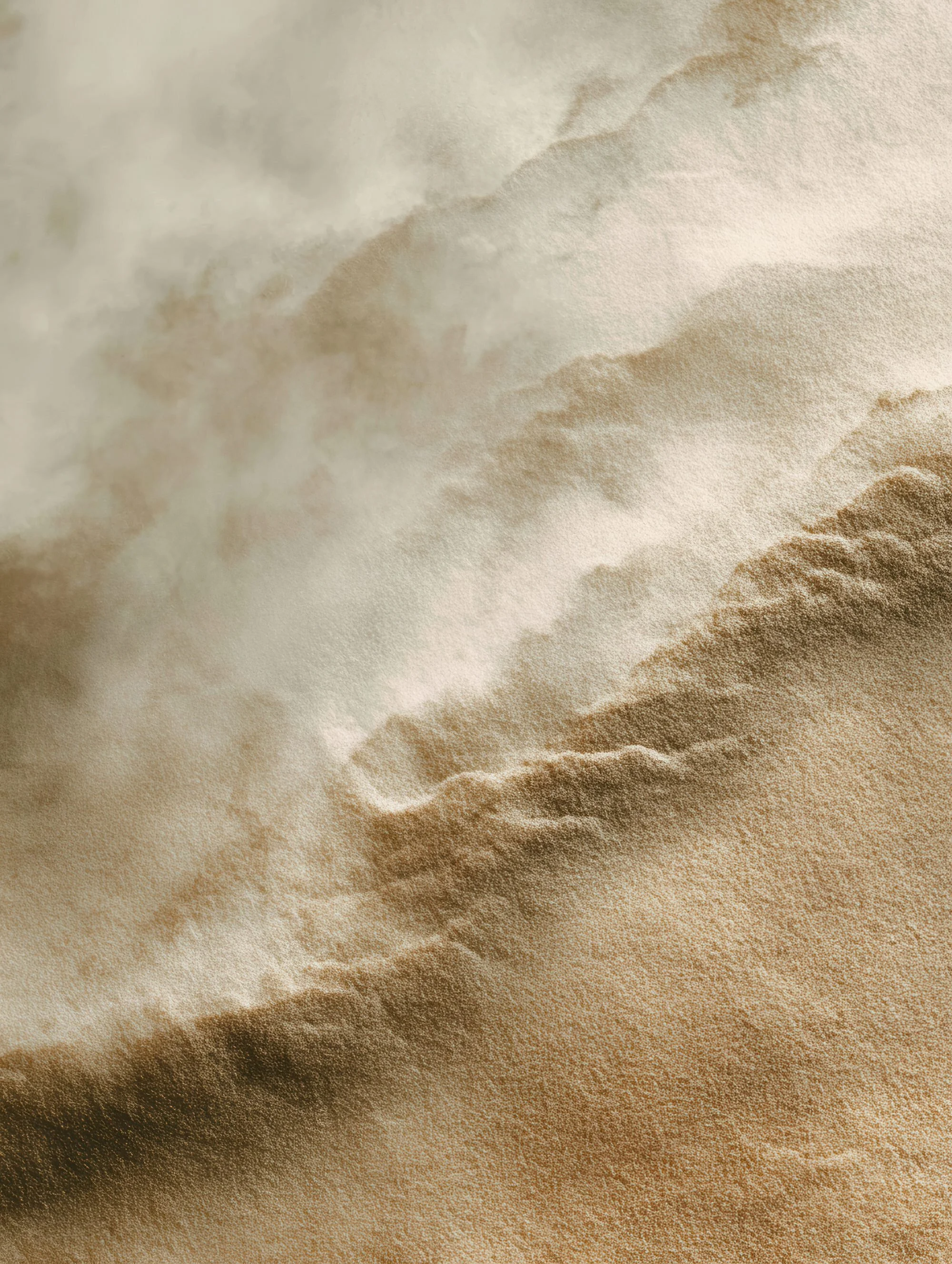 Close-up of a sand dune with smooth, flowing ridges and shadows, in shades of beige and brown.