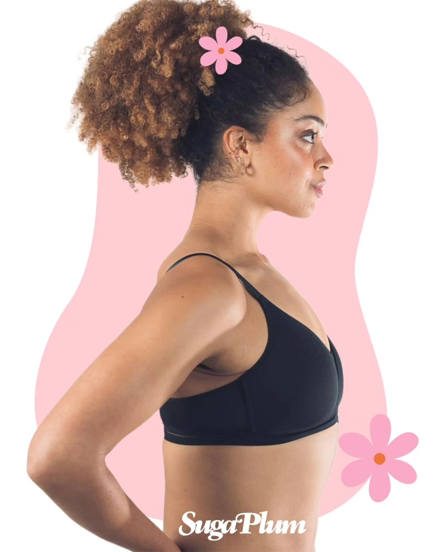 Side profile of a woman with curly brown and black hair, wearing a black sports bra, standing with her hand on her waist, against a pink background with flower illustrations, with the word "SugaPlum" at the bottom.