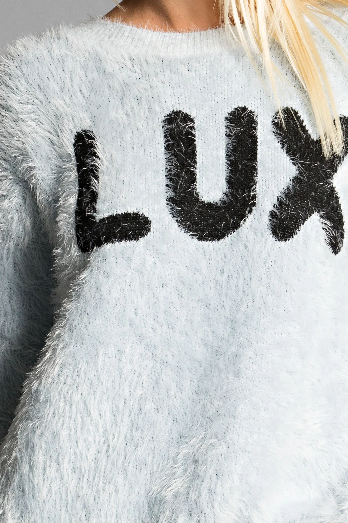 Close-up of a person wearing a fuzzy gray sweater with the word 'luv' in large black letters.