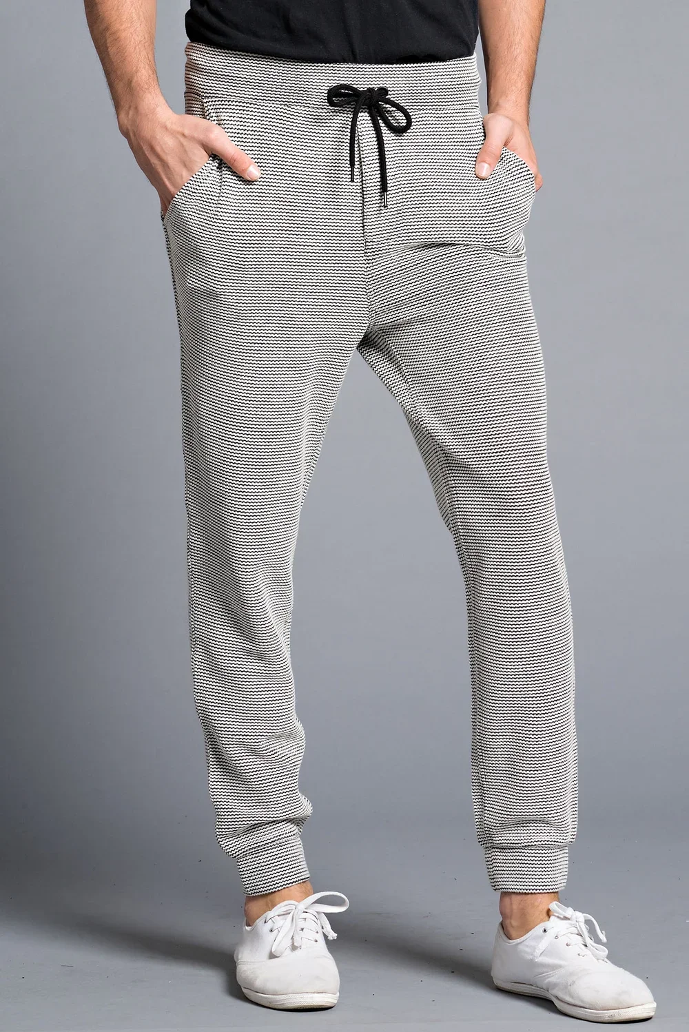 Person wearing patterned jogger pants with hands in pockets and white sneakers.