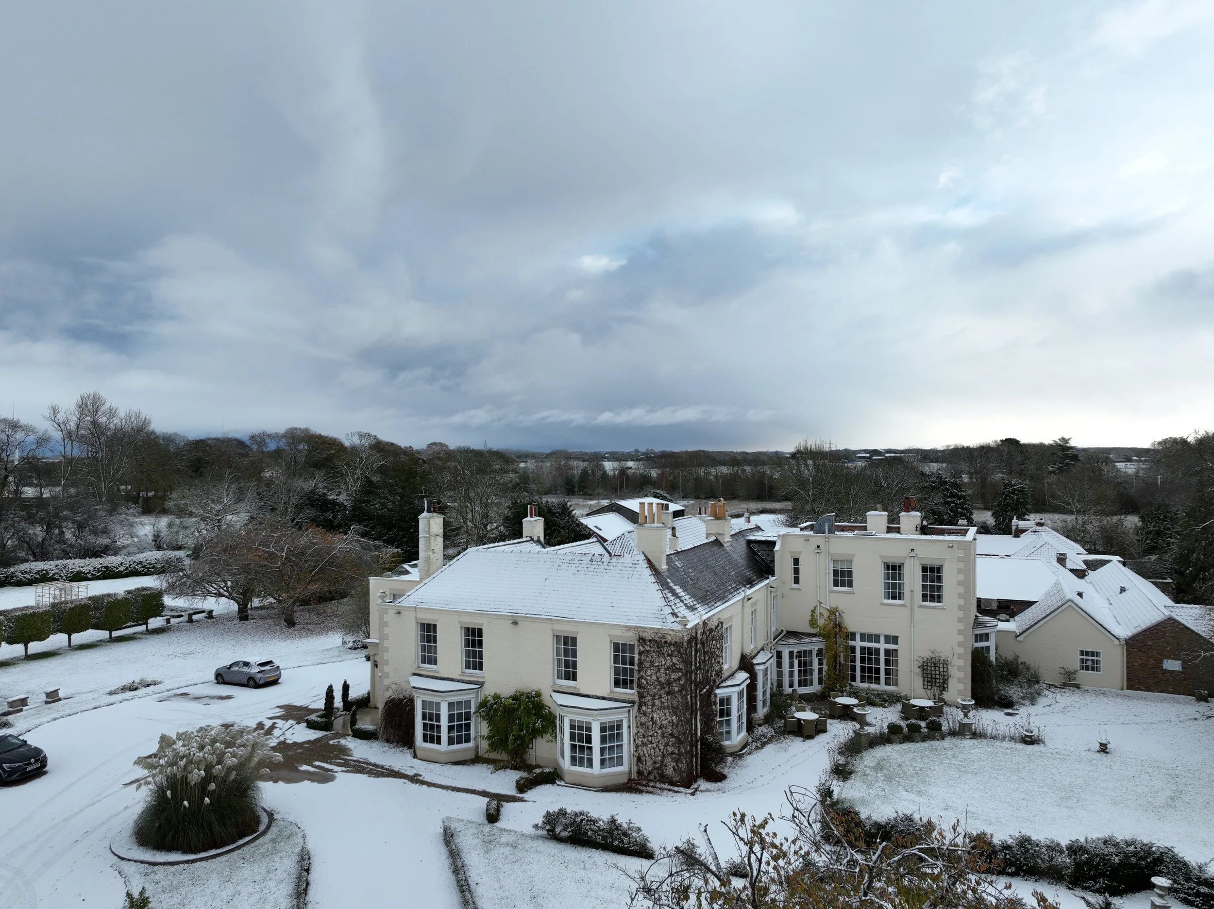 A drone shot of Tickton Grange, taken in the winter showing snow covered roof and grounds beneath a cloudy sky.