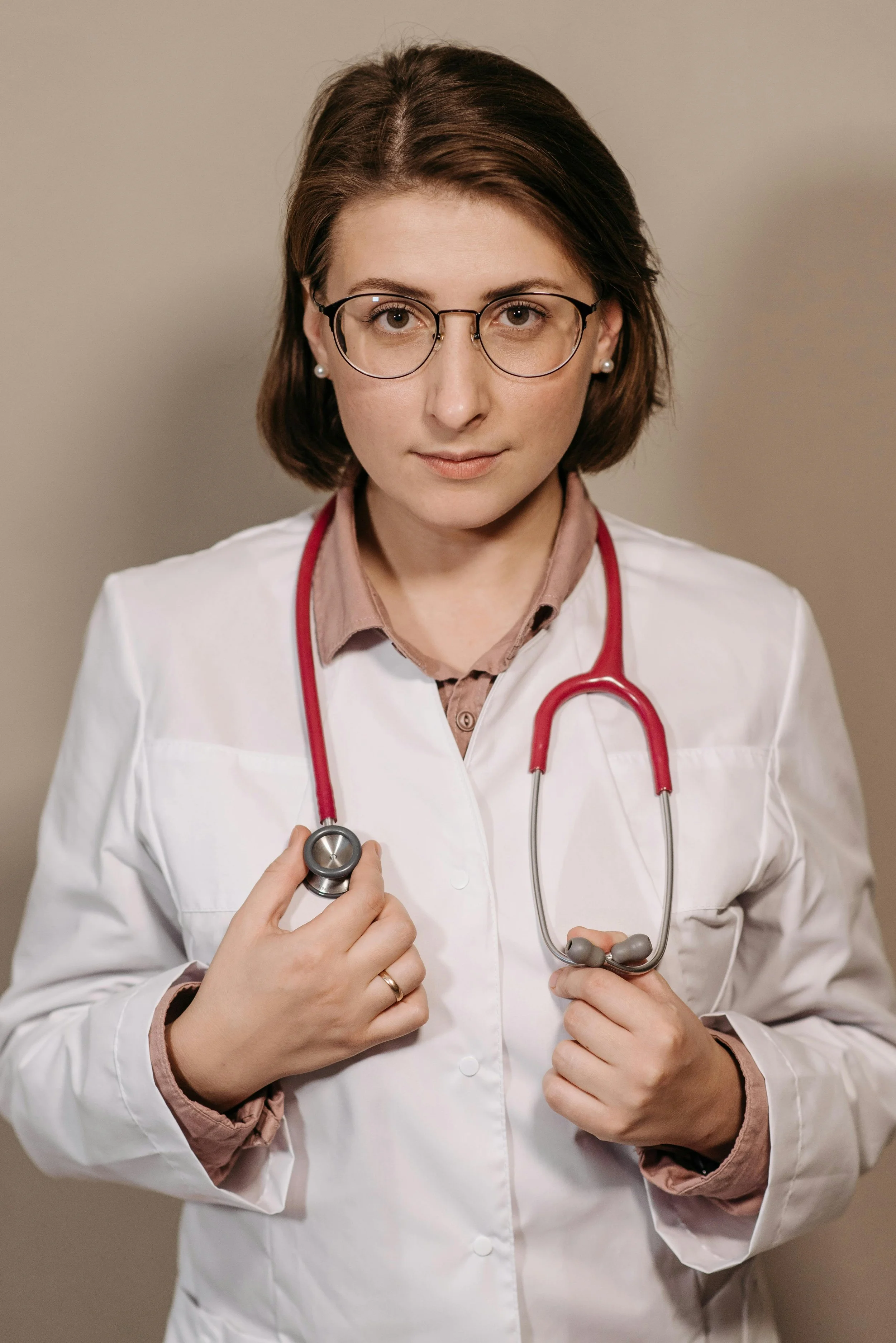woman with short brown hair wearing white doctor jacket with a stethoscope