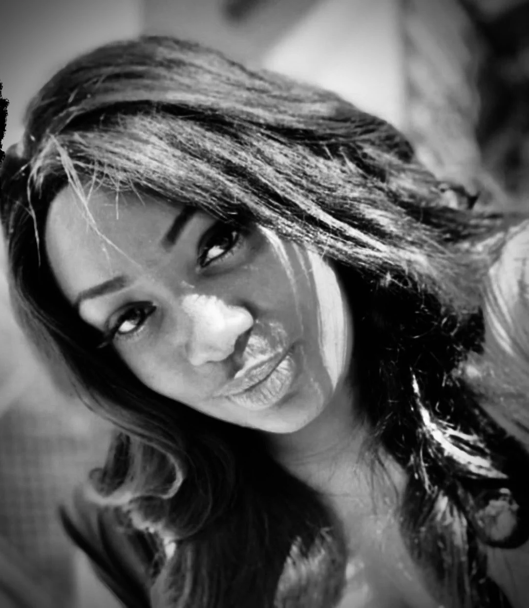 Black and white portrait of a woman smiling, with long curly hair, looking at the camera.